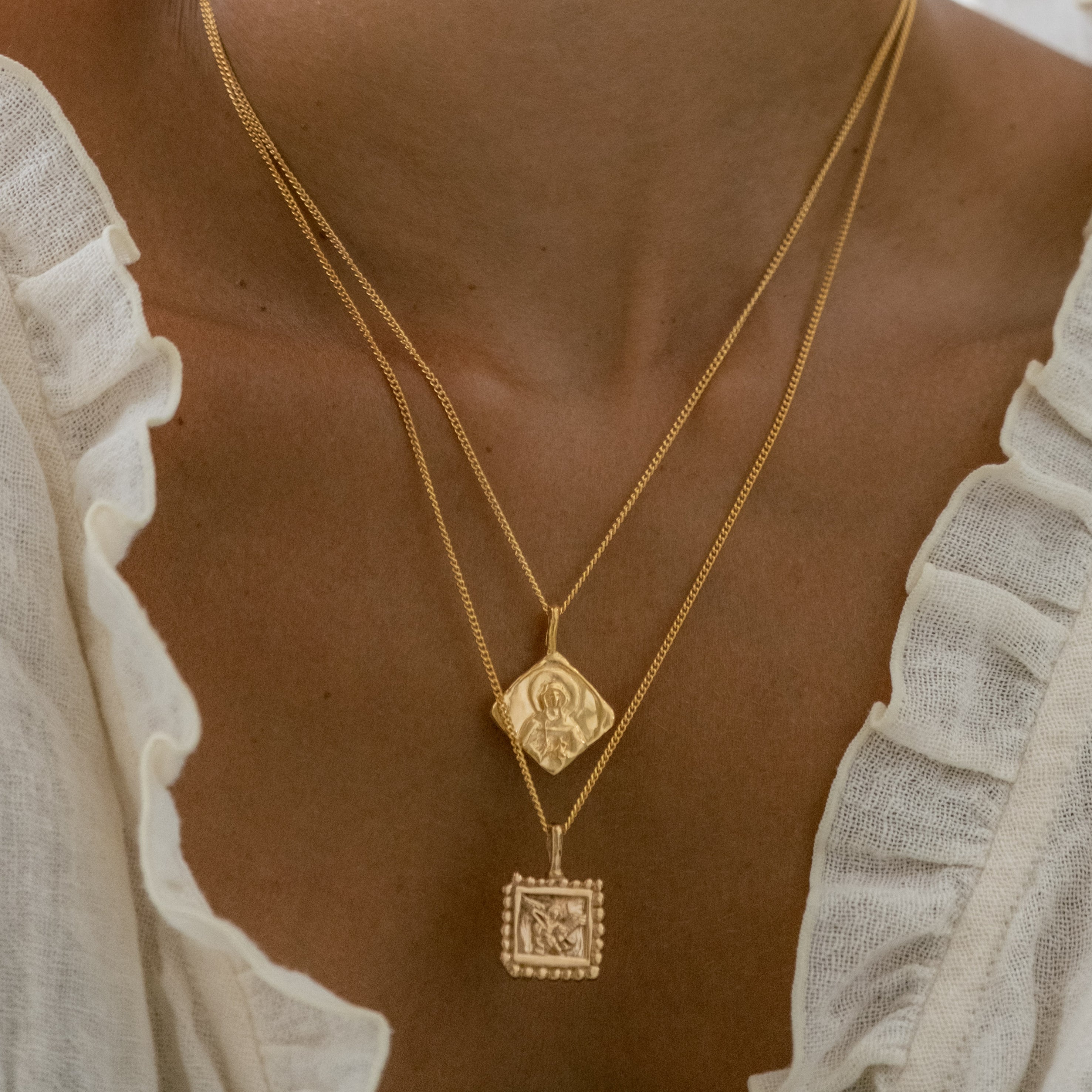 a woman with white dress wearing two necklaces gold