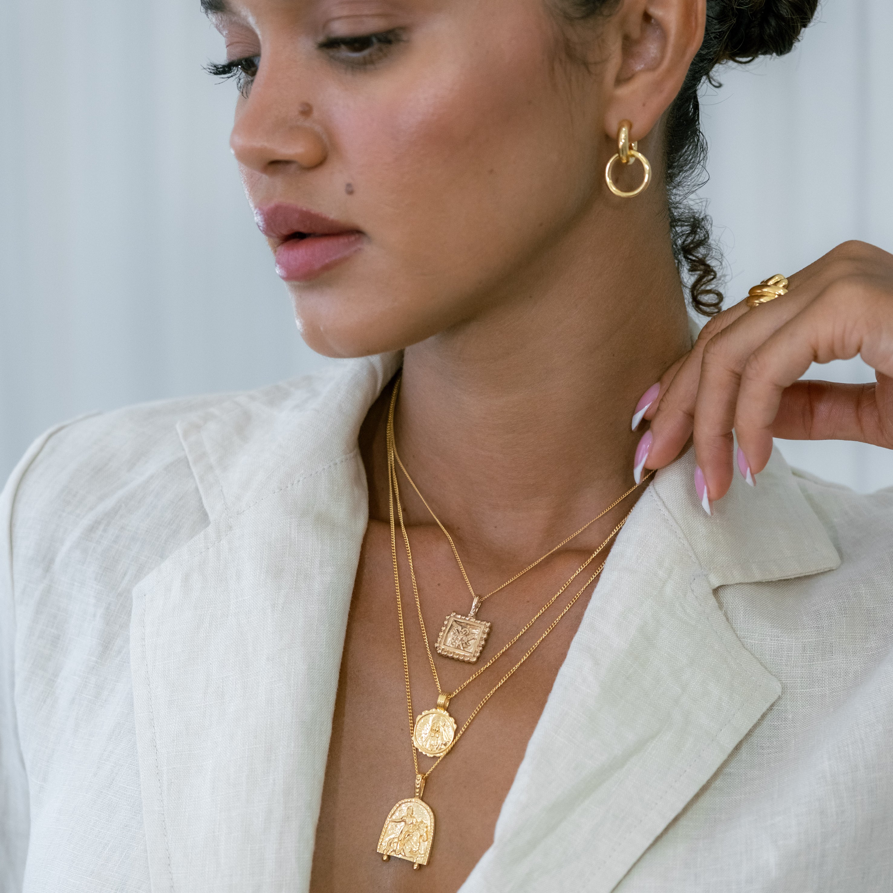 a woman wearing three layered necklaces gold