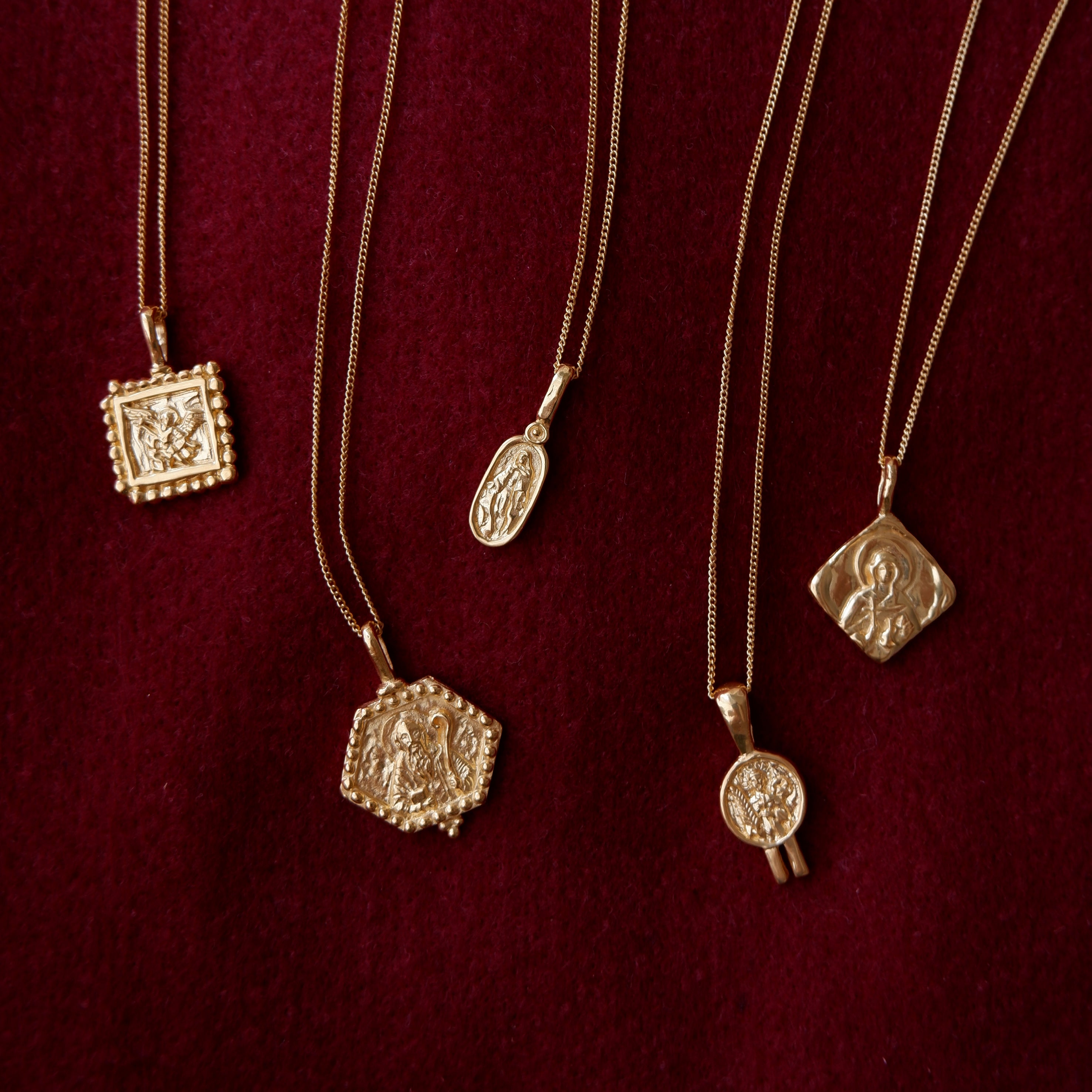 five necklaces gold flat lay in red fabric