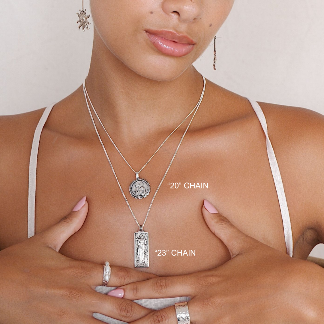 Woman wearing two silver necklaces with labeled chain lengths on a neutral background