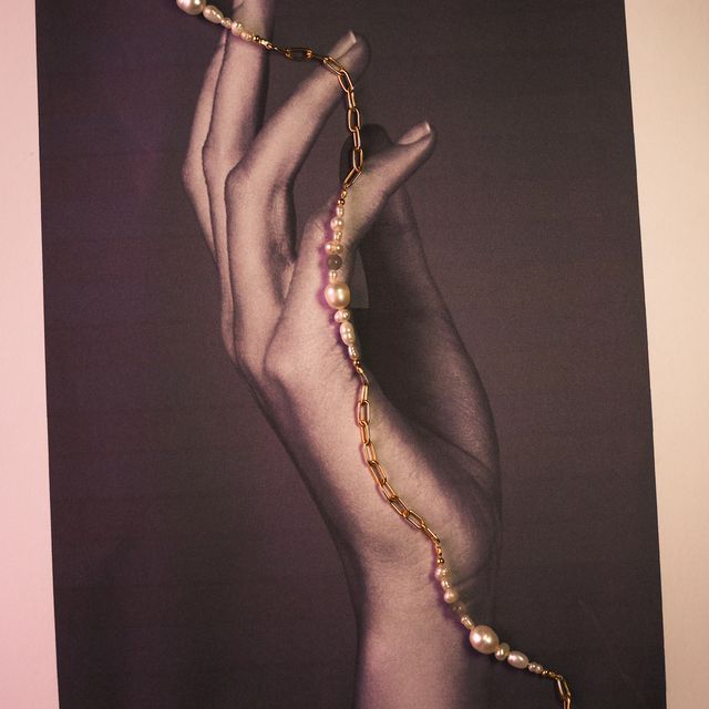 Minimalist display of a pearl necklace on a photo paper surface