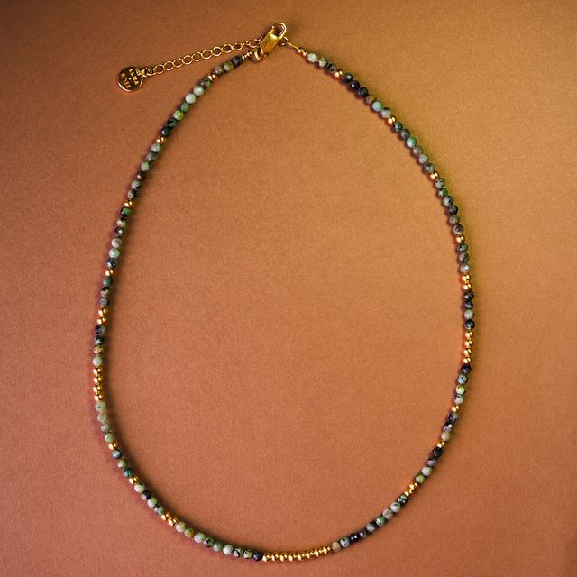 Gemstone necklace laid on glossy brown paper