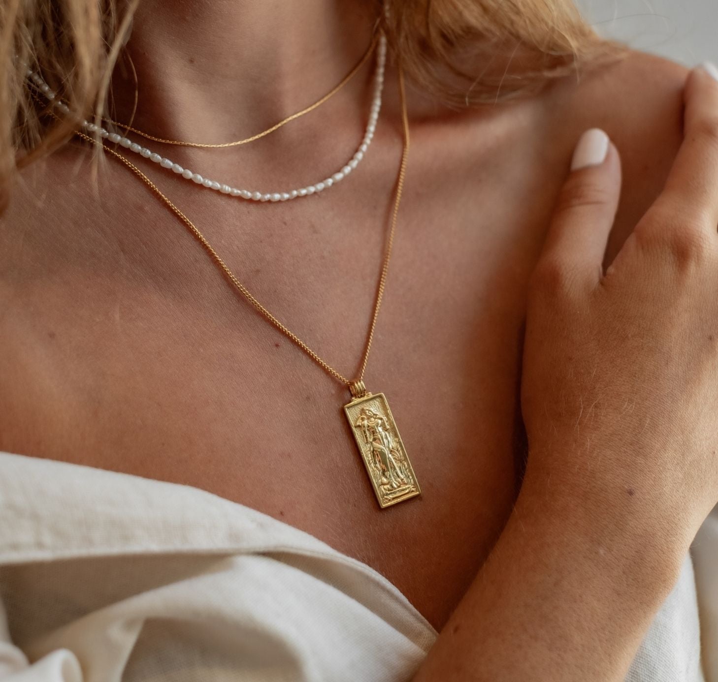 a woman with white linen shirts wearing Freyja Goddess of Love Pendant gold and timeless mini pearl necklace