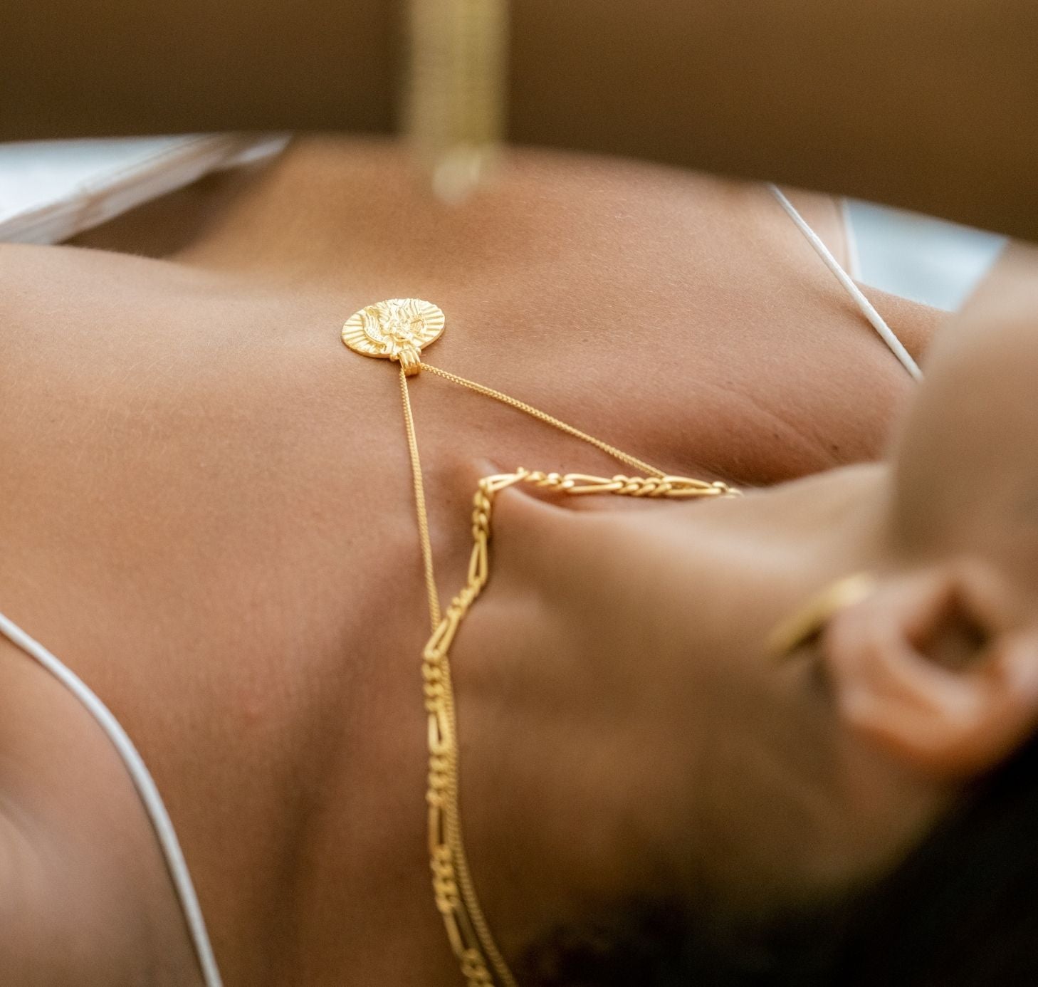 two layering necklaces on a woman lying down