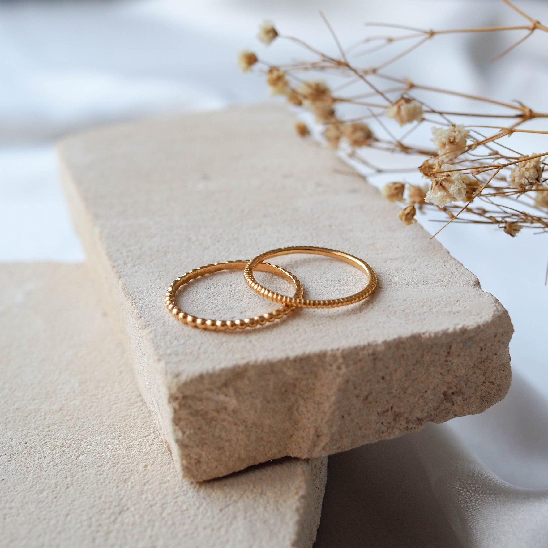 The MET Stripe Band - Gold displayed on beige stone