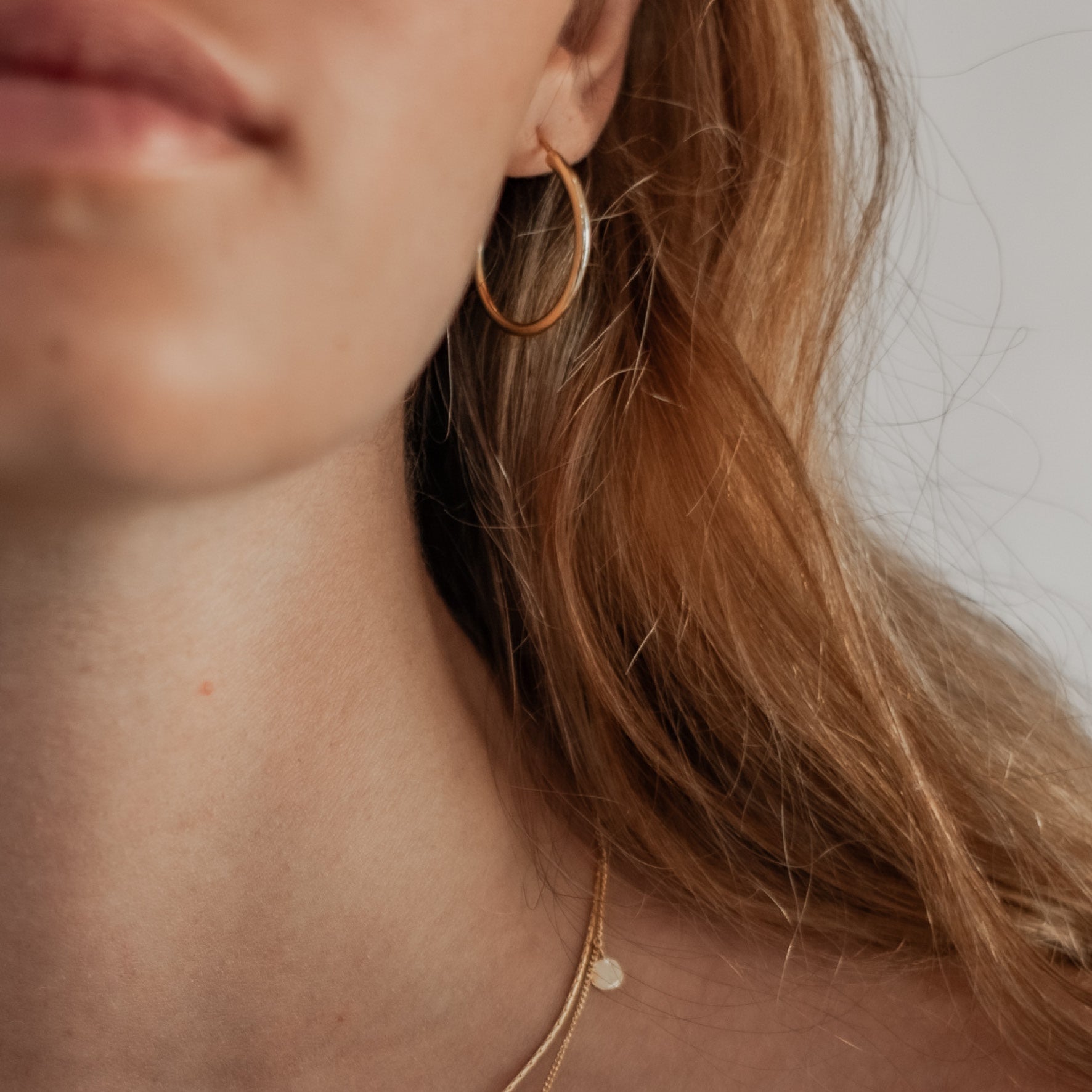 a woman with blonde hair worn necklace gold and hoops earrings gold