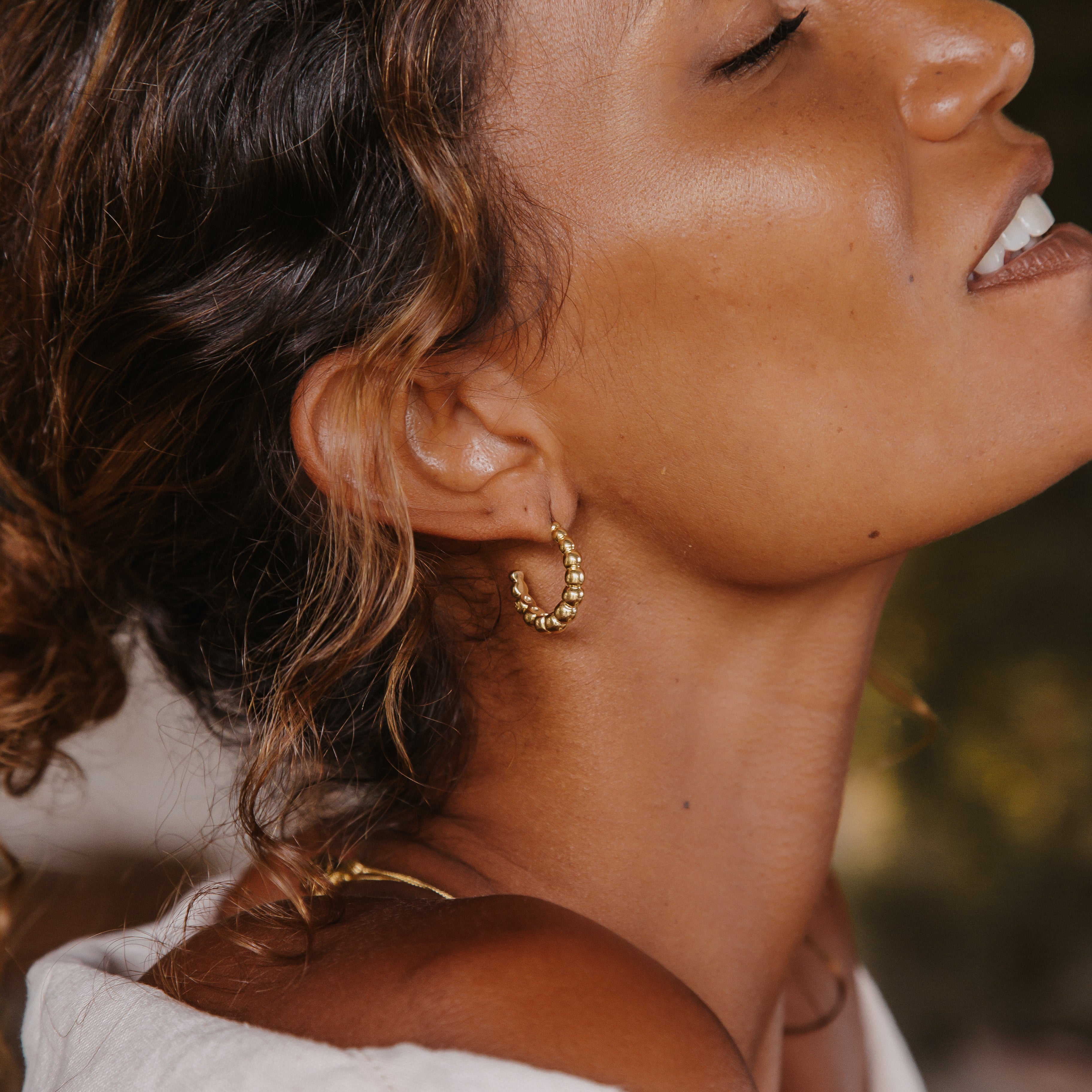A woman with brown hair wearing a small golden hoop earring