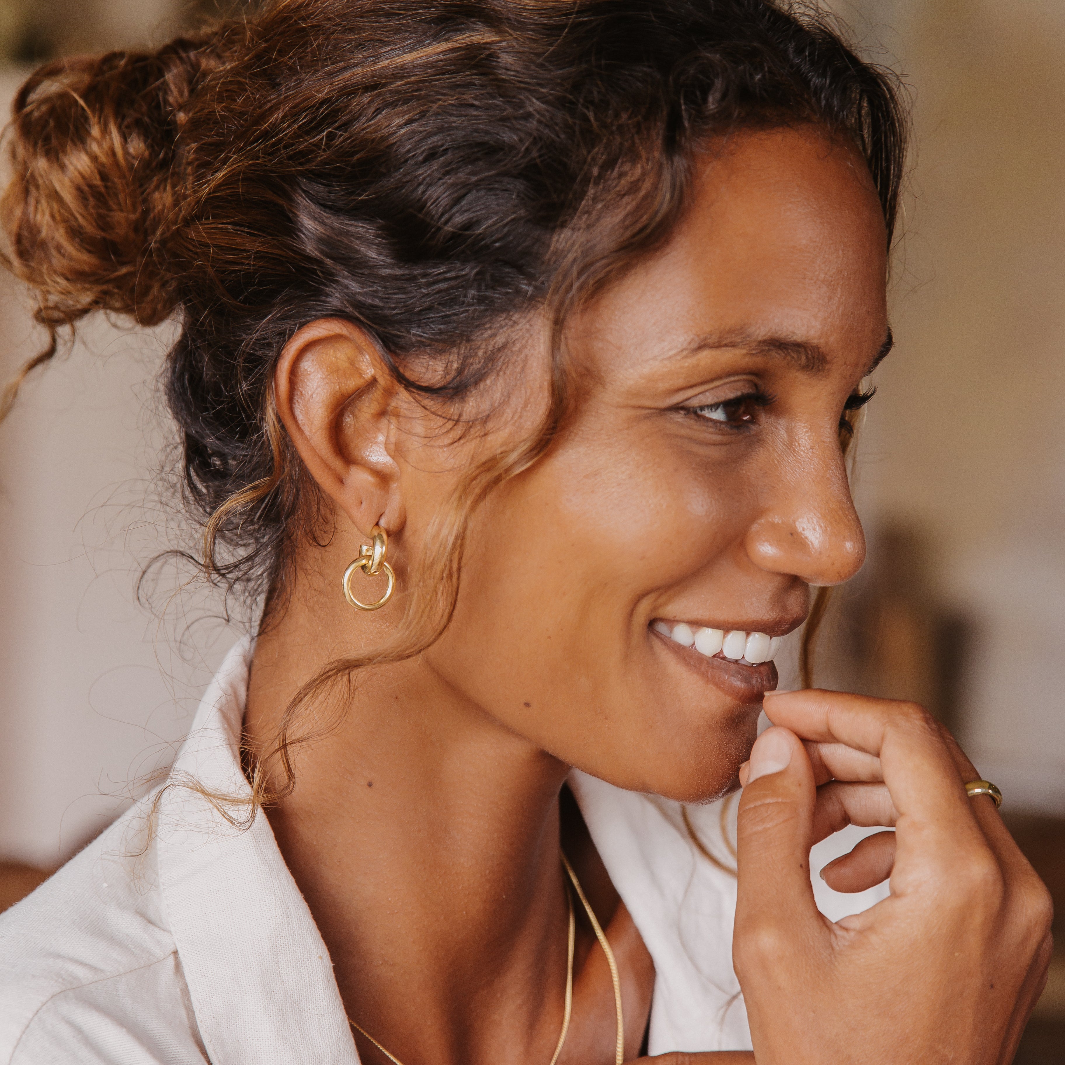 A side view of a woman wearing the double hoop gold earrings, with her hair styled back to showcase the jewelry.