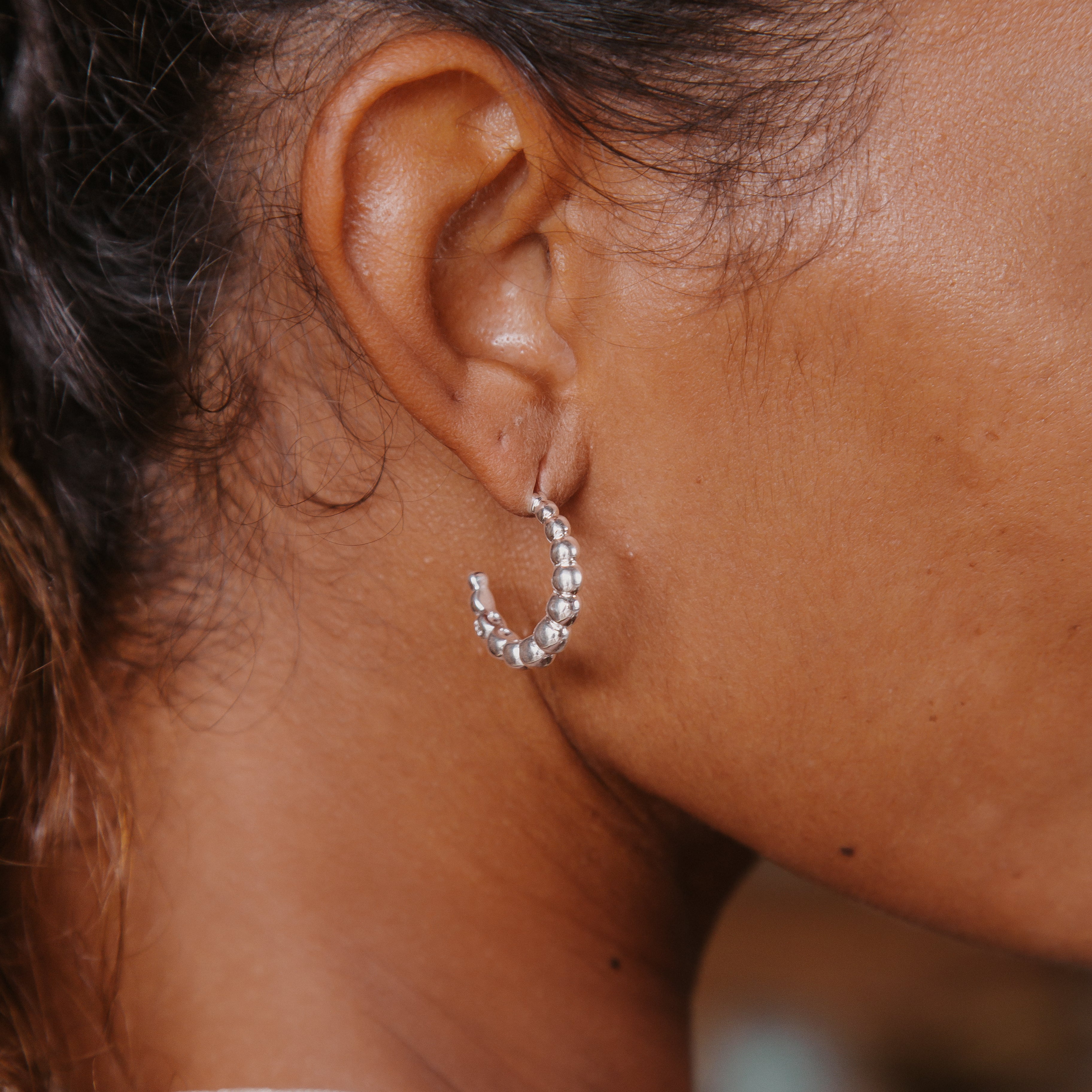 Close-up of a woman with brown hair wearing a silver earring