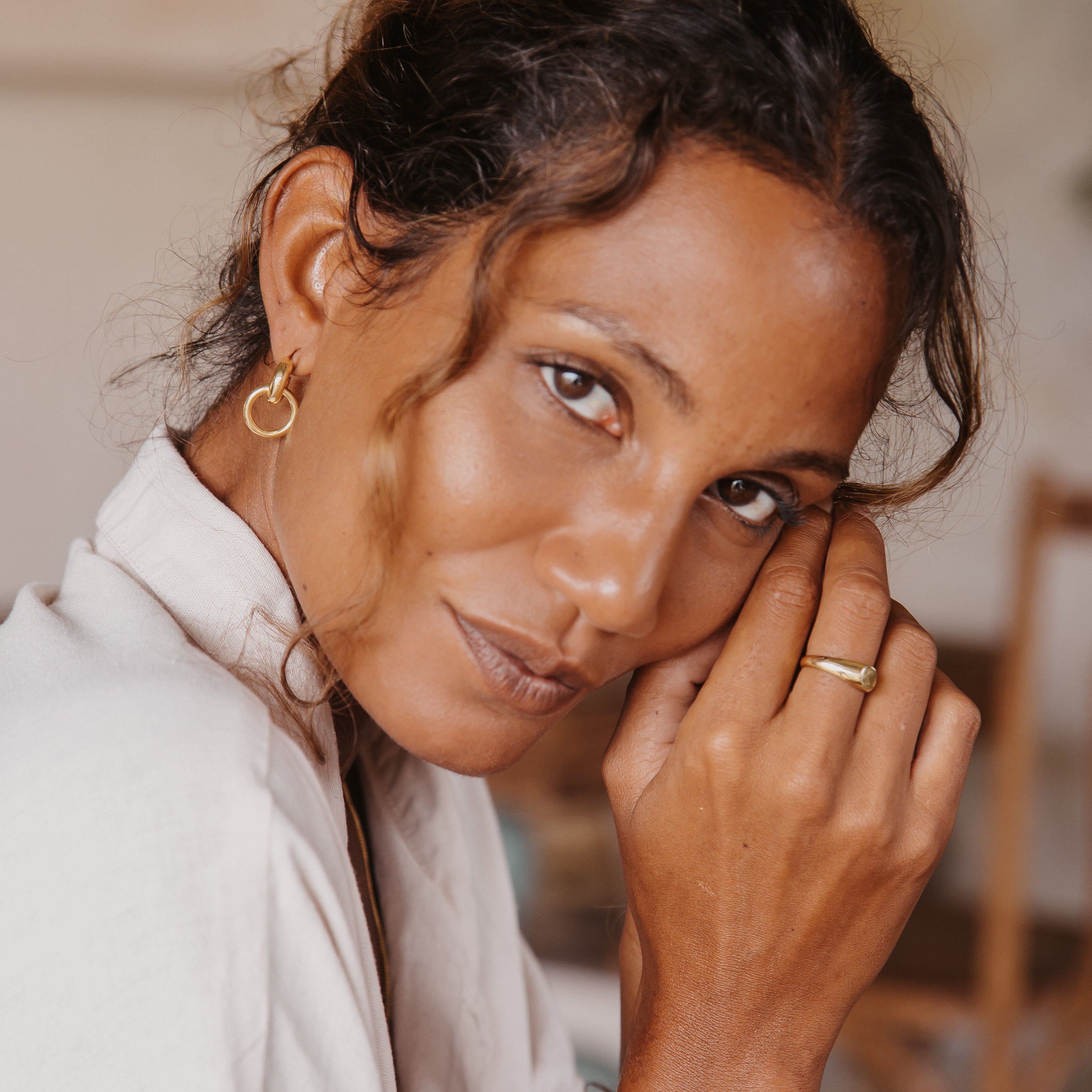 A woman looking into the camera and wearing the double hoop gold earrings.