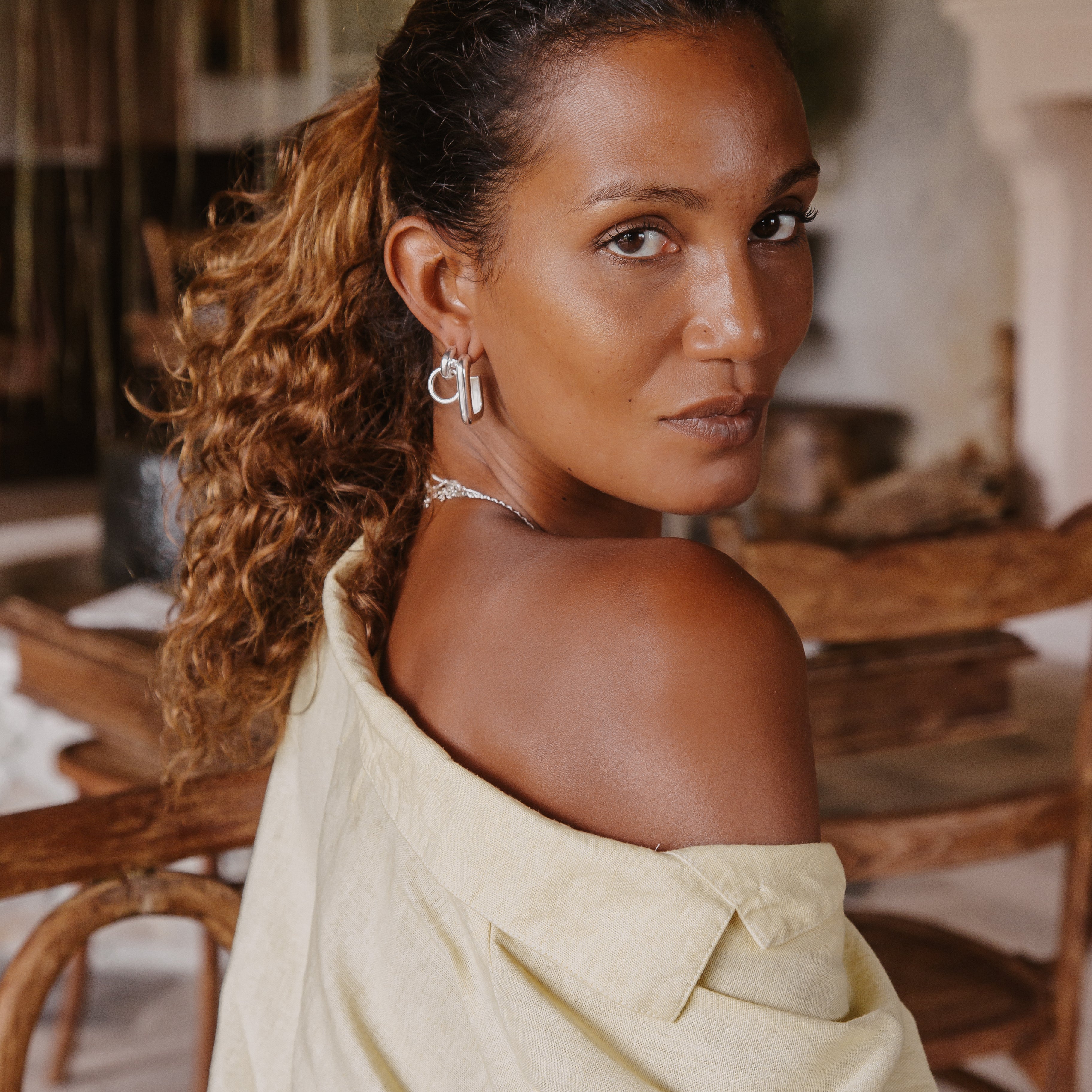 A woman looking into the camera and wearing the double hoop silver earrings.