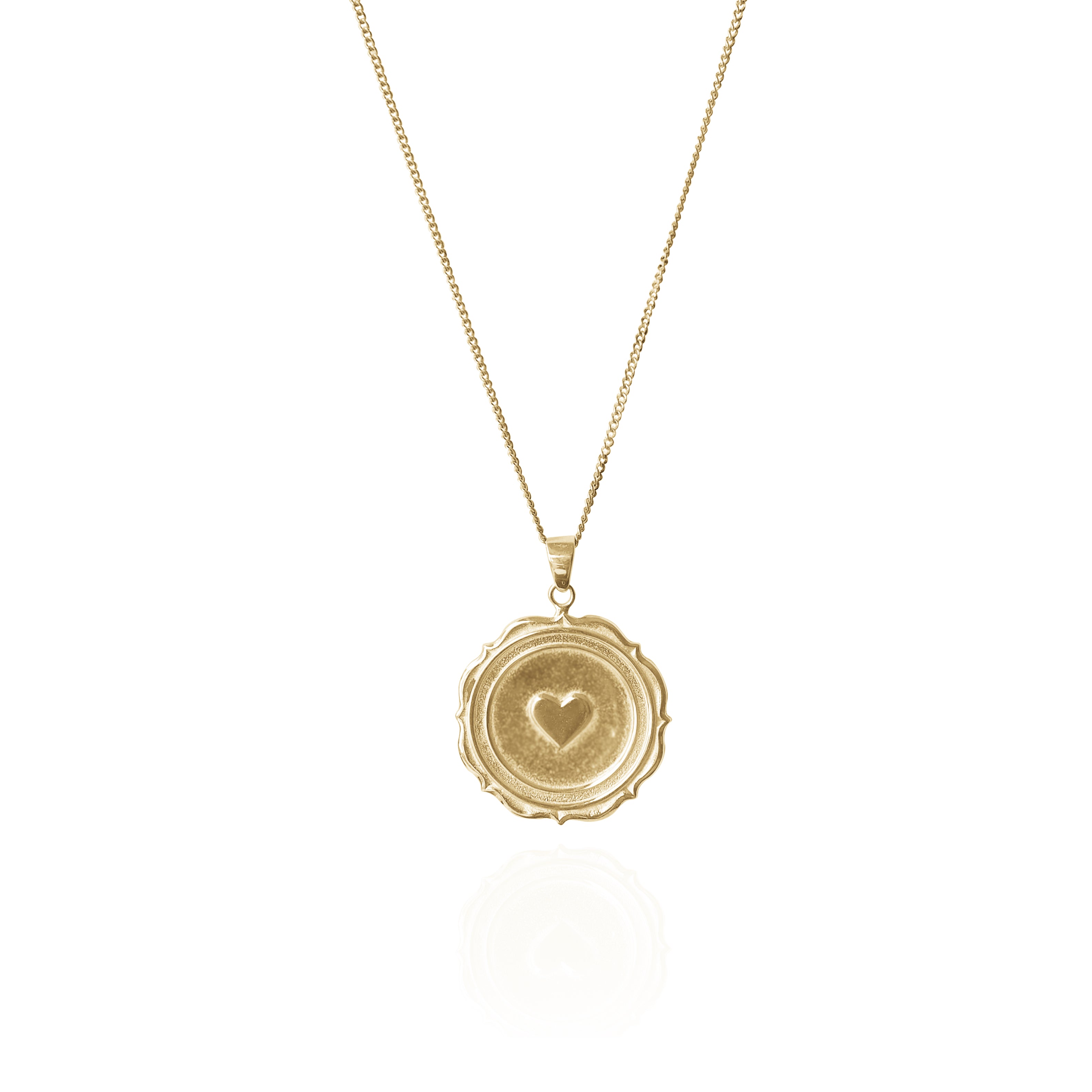 A gold necklace with a round pendant featuring a raised heart design, displayed against a white background.