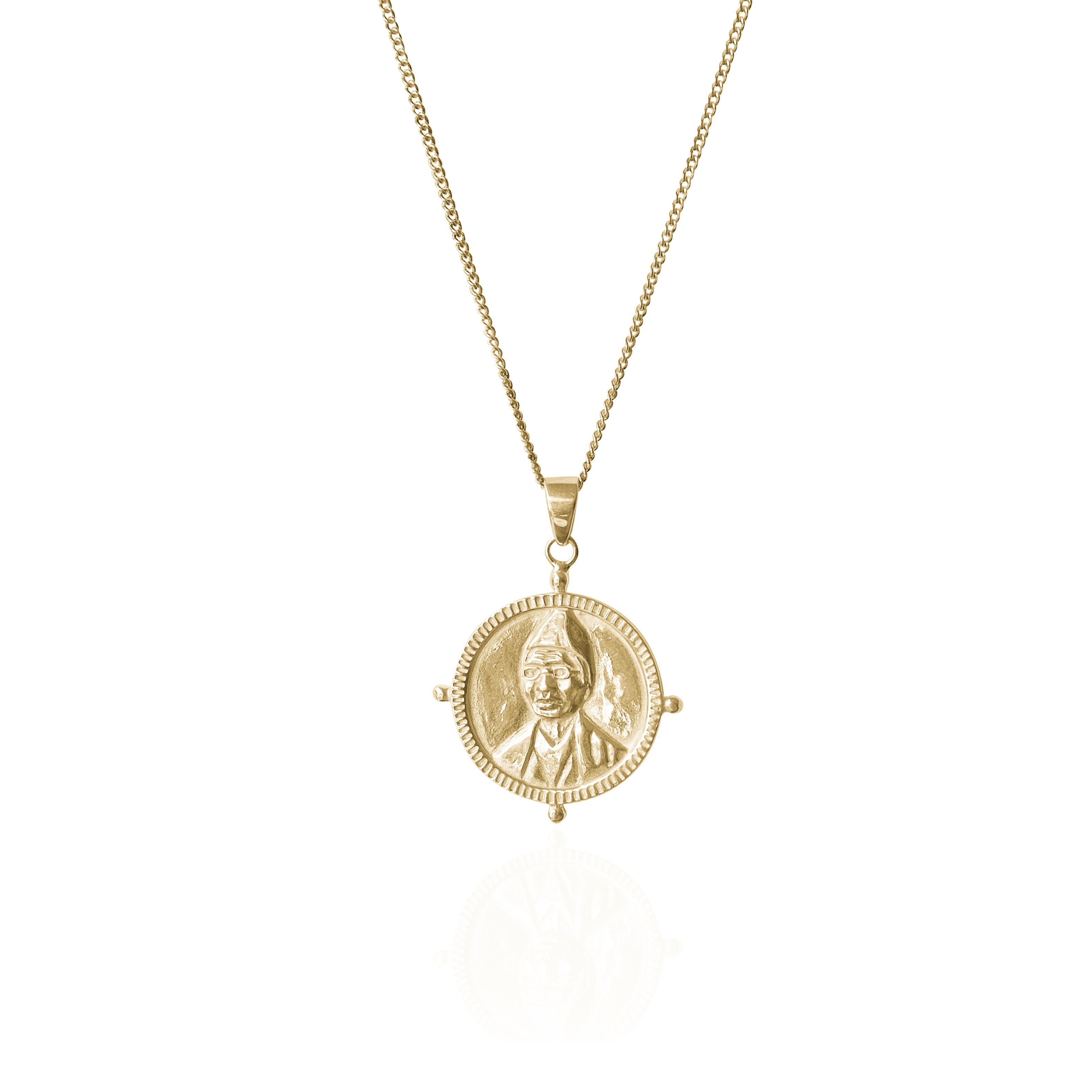 A gold necklace with a round pendant featuring a raised portrait design, displayed against a white background.