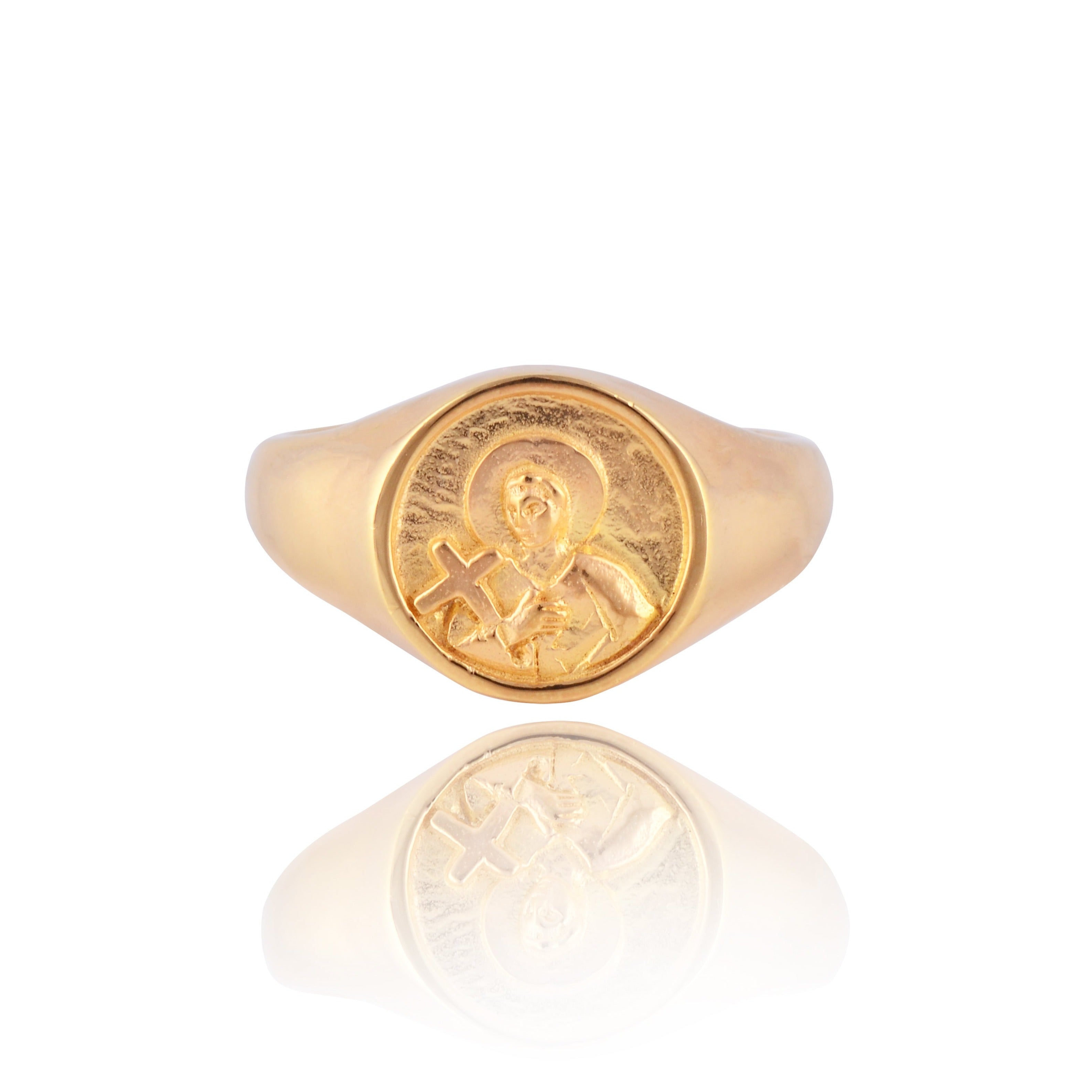 A gold signet ring with a round face featuring a raised religious figure design, displayed against a white background.