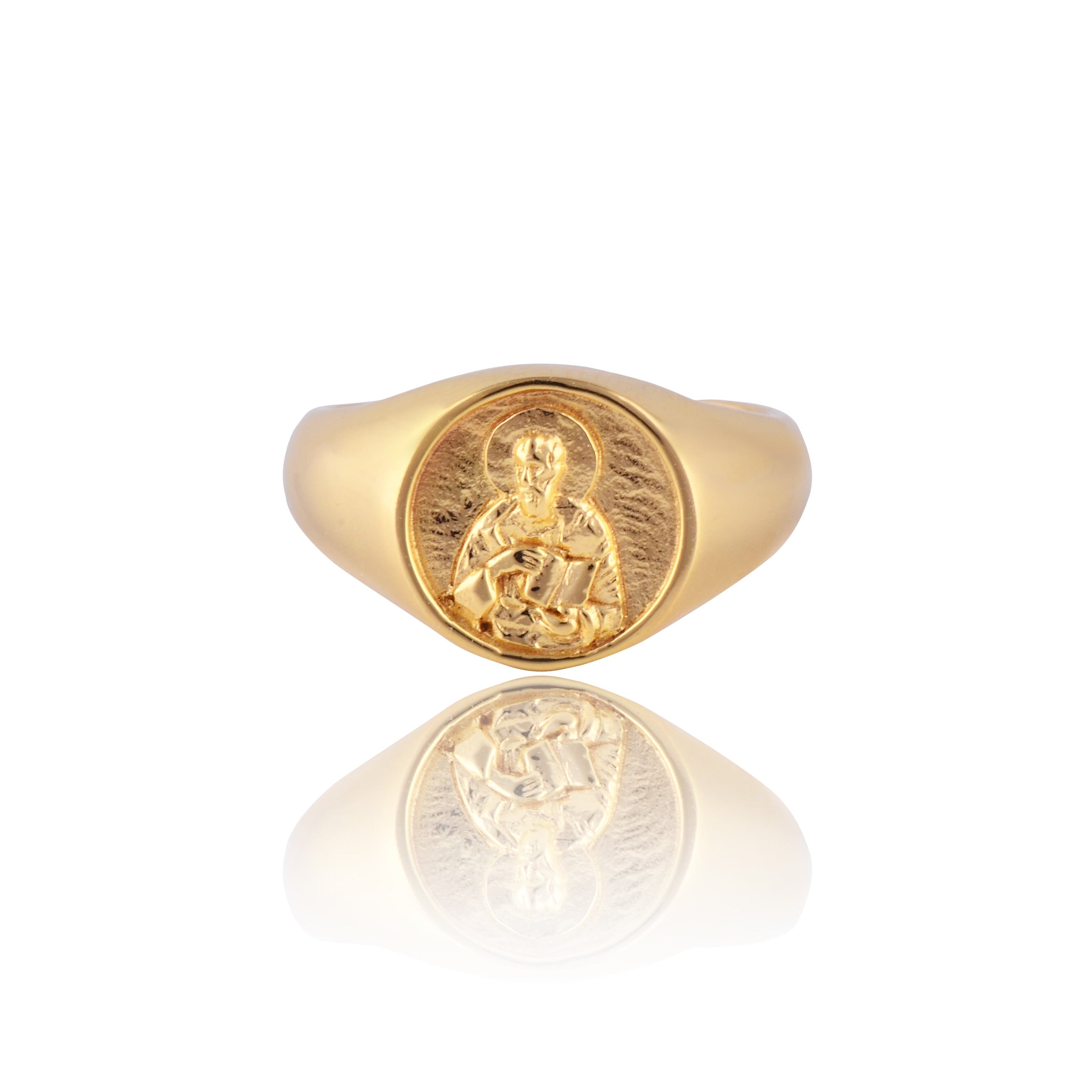 A gold signet ring featuring an intricately detailed depiction of a saint figure holding a book on its face.