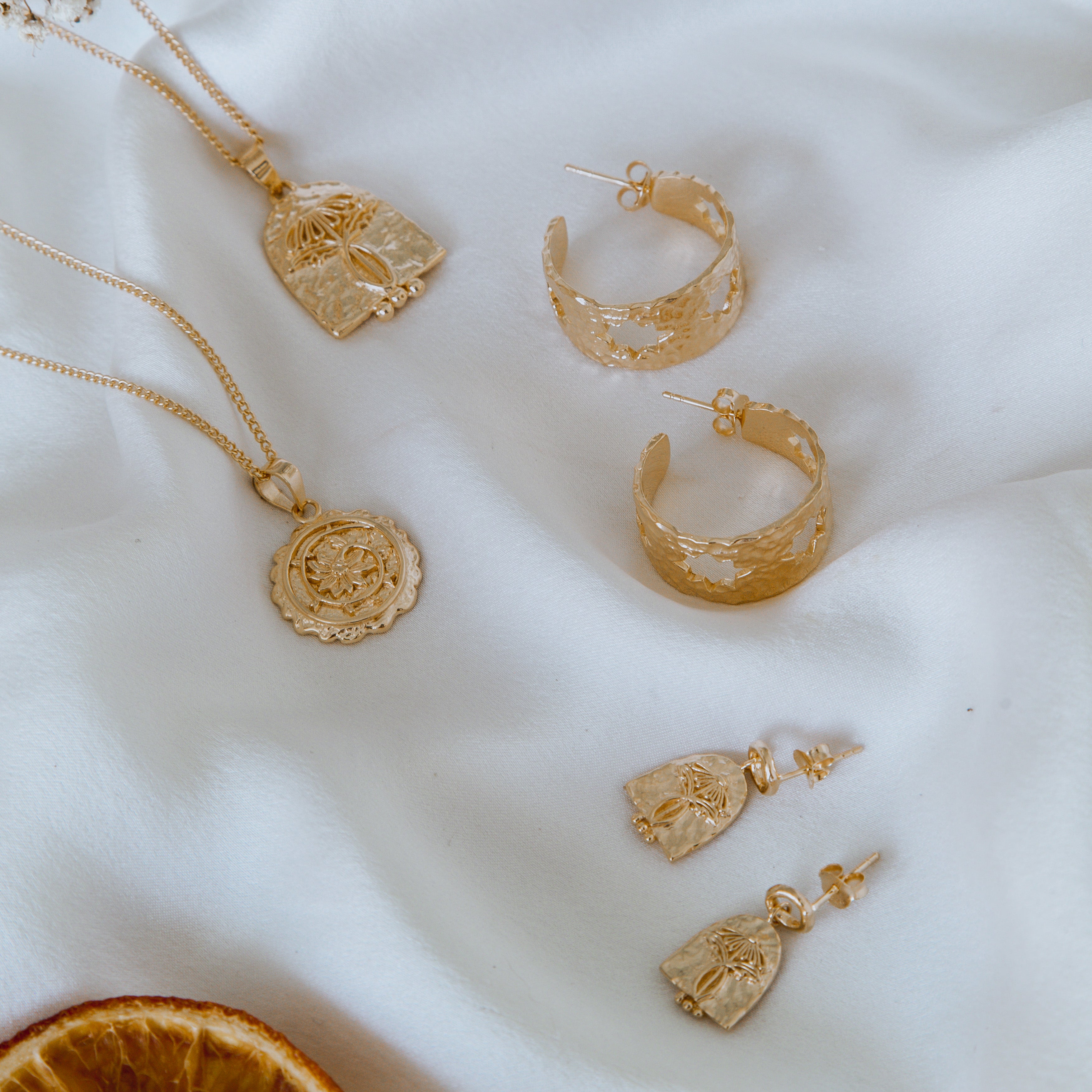 A set of jewellery displayed against a white satin background