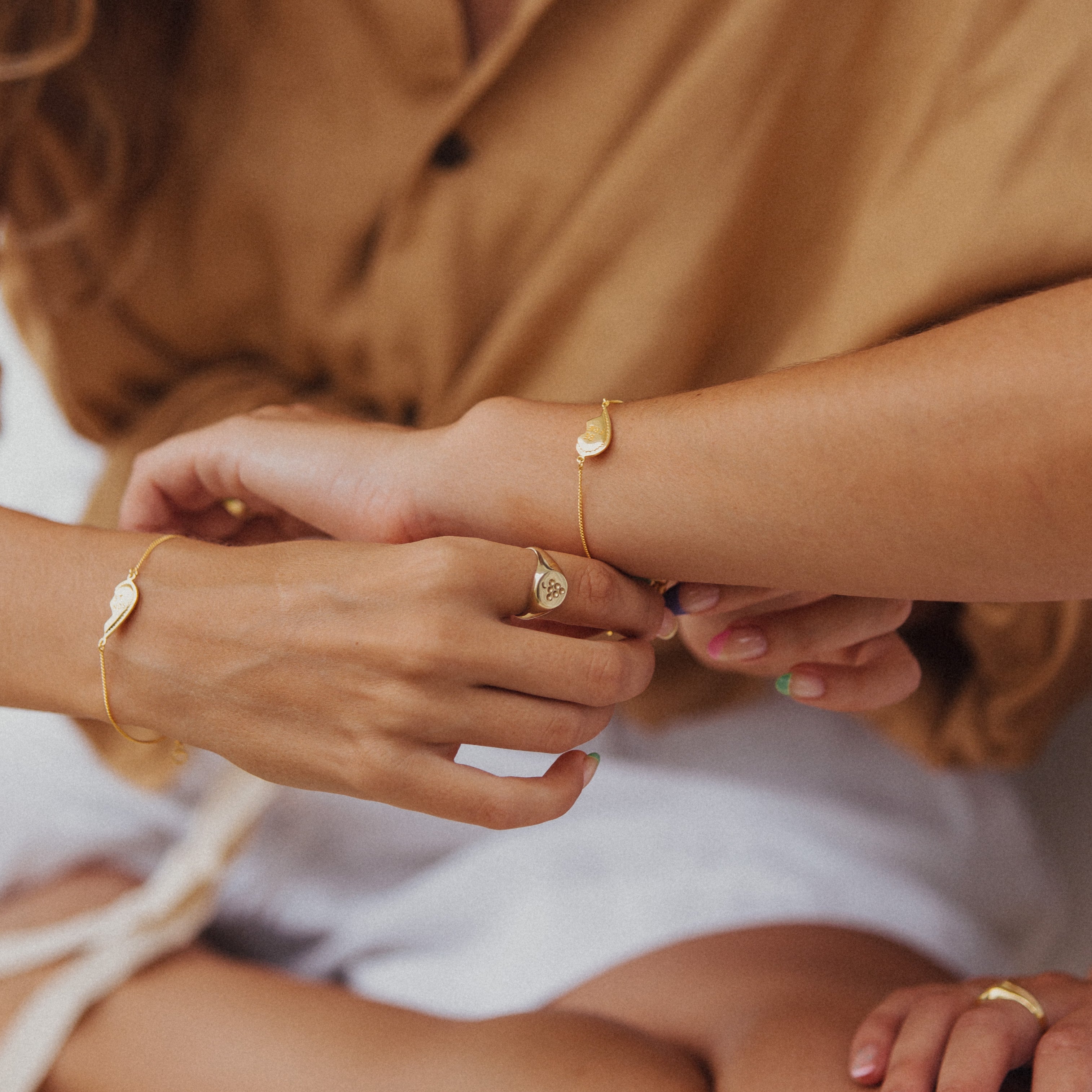 A woman putting on a BFF Broken Heart Bracelet on another woman's arm
