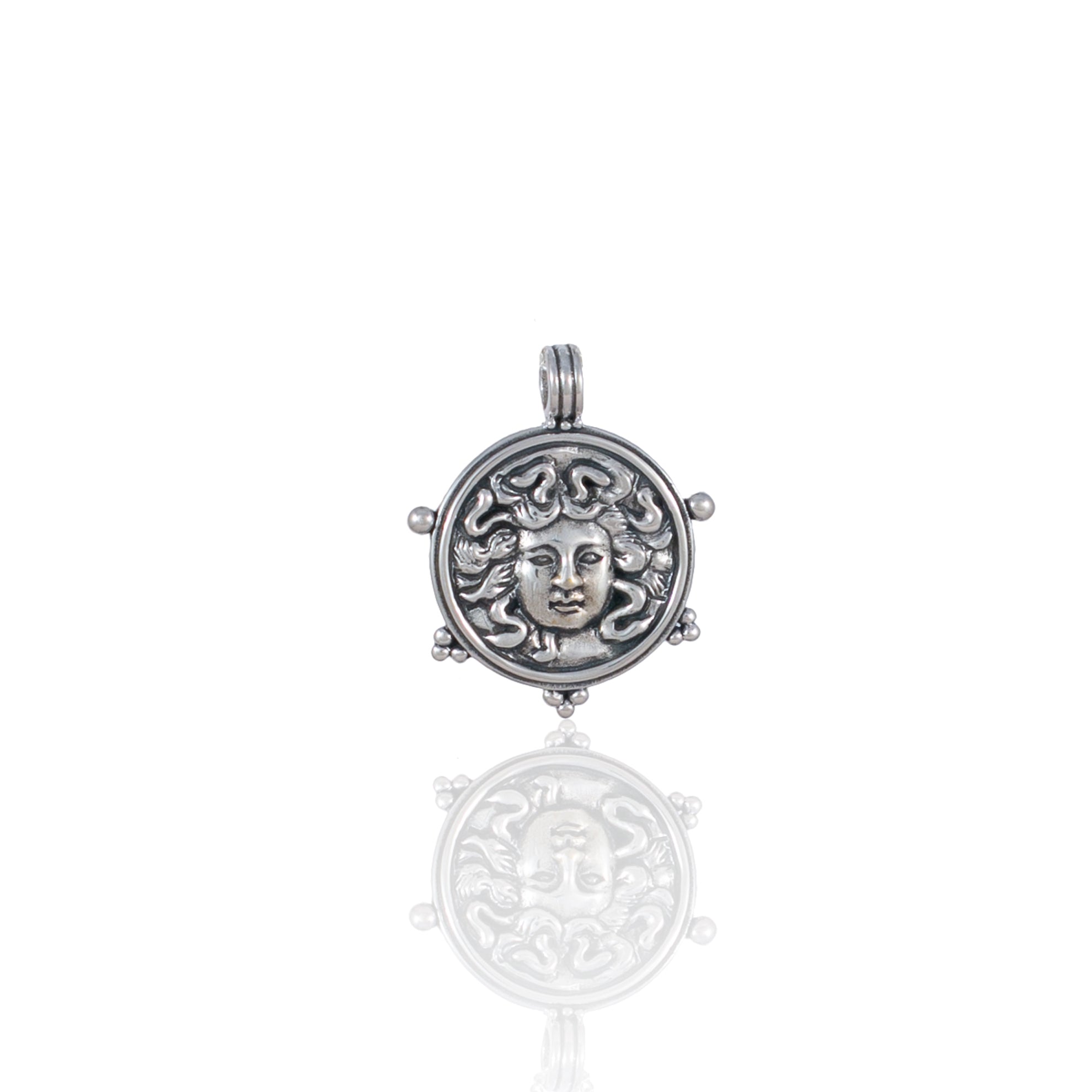 Silver pendant featuring a detailed Medusa face design with reflective surface.
