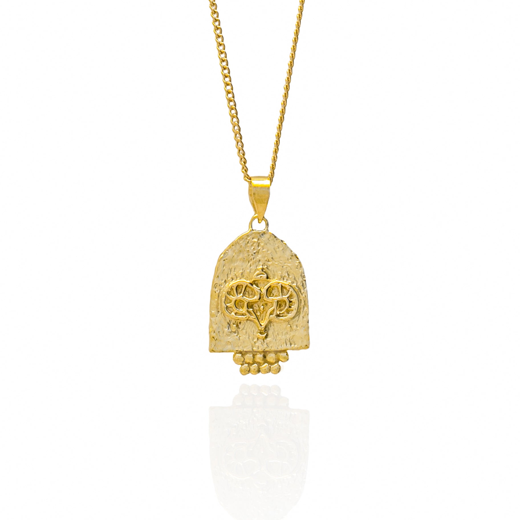 A gold pendant featuring an engraved design on a white background.