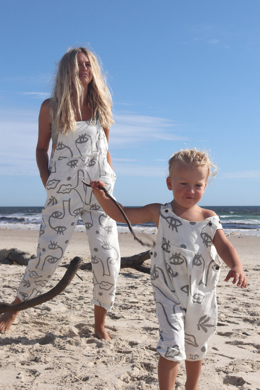 A toddler walking away with a wooden stick on the beach