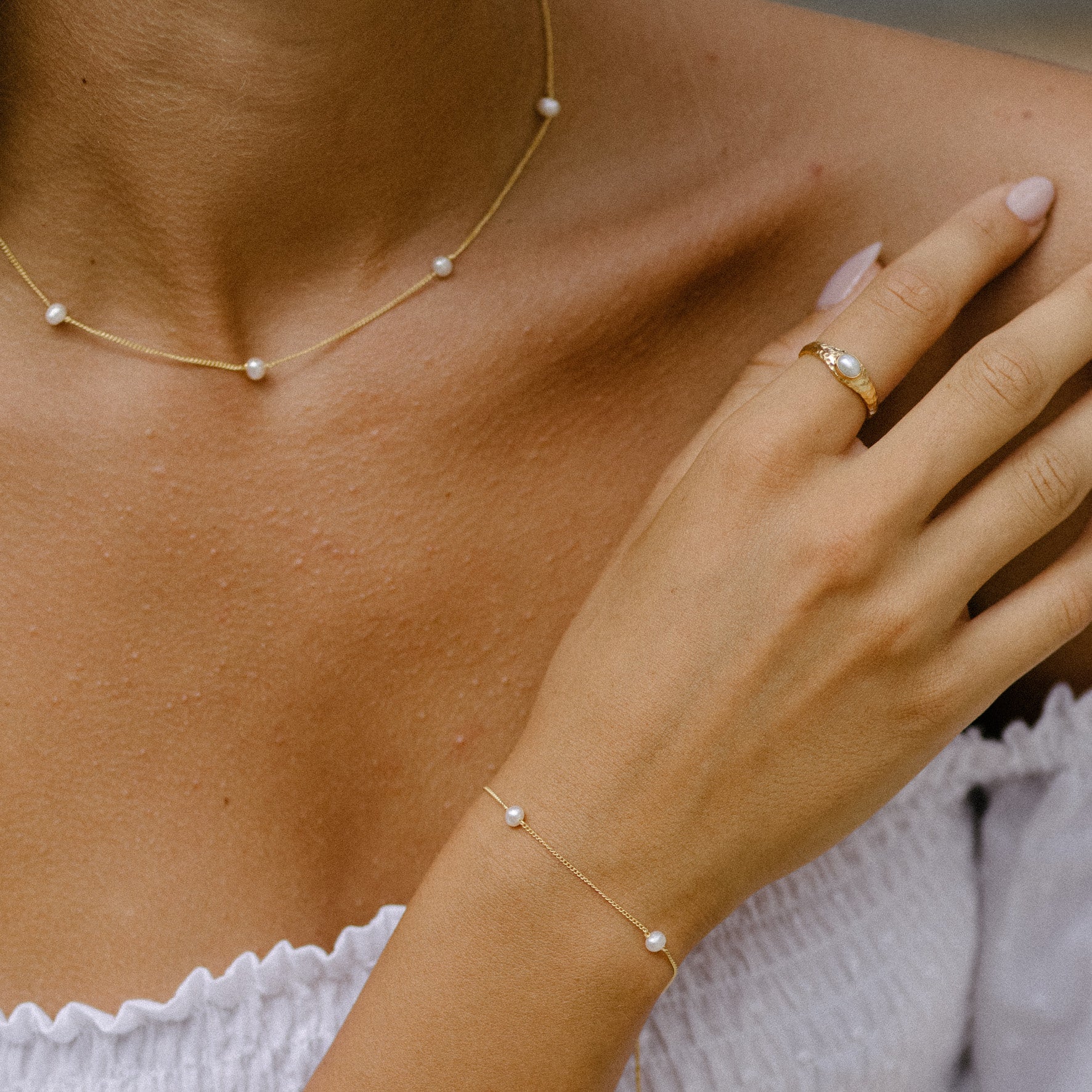 a woman with white dress wearing The Maisy chain necklace, The Maisy bracelet and Pia ring gold