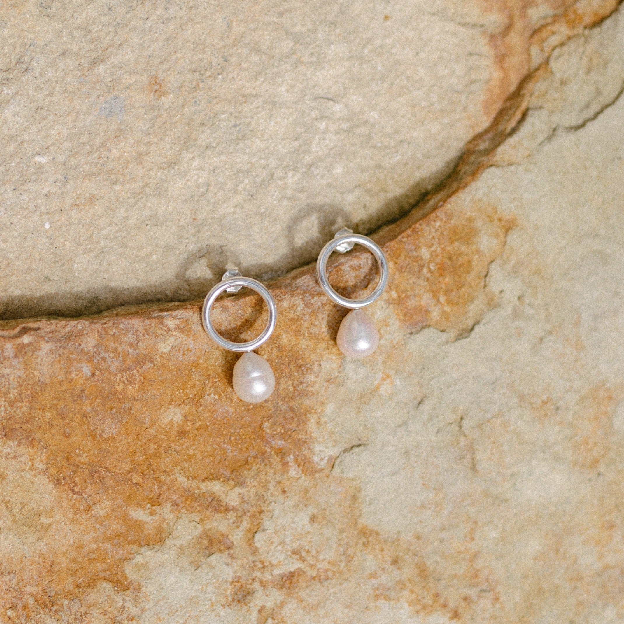 River pearl earrings silver displayed on beige stone