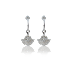 A pair of silver earrings with a circular sunburst design on a white background.