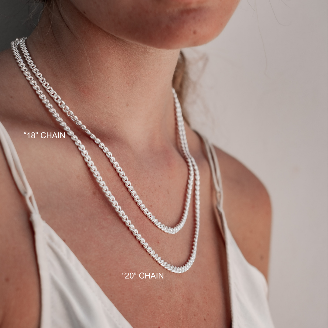 Two silver chain necklaces on a person's neck with labels indicating lengths.