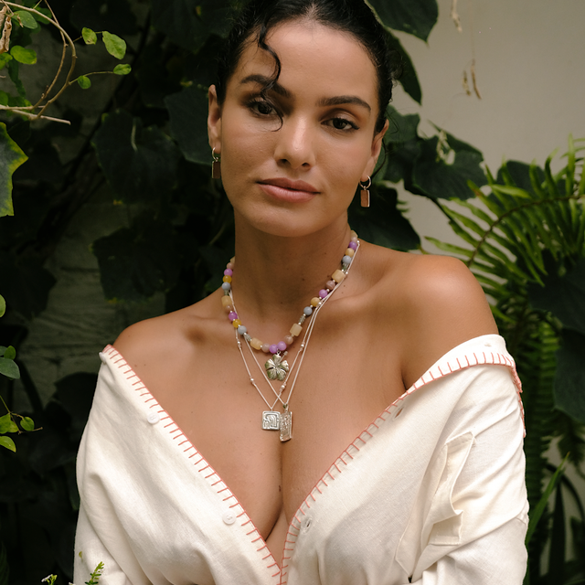 Close-up of a woman in a white shirt wearing a silver necklace and accessories by luna rose
