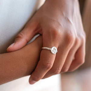 A close-up of two hands wearing a silver ring on the index finger