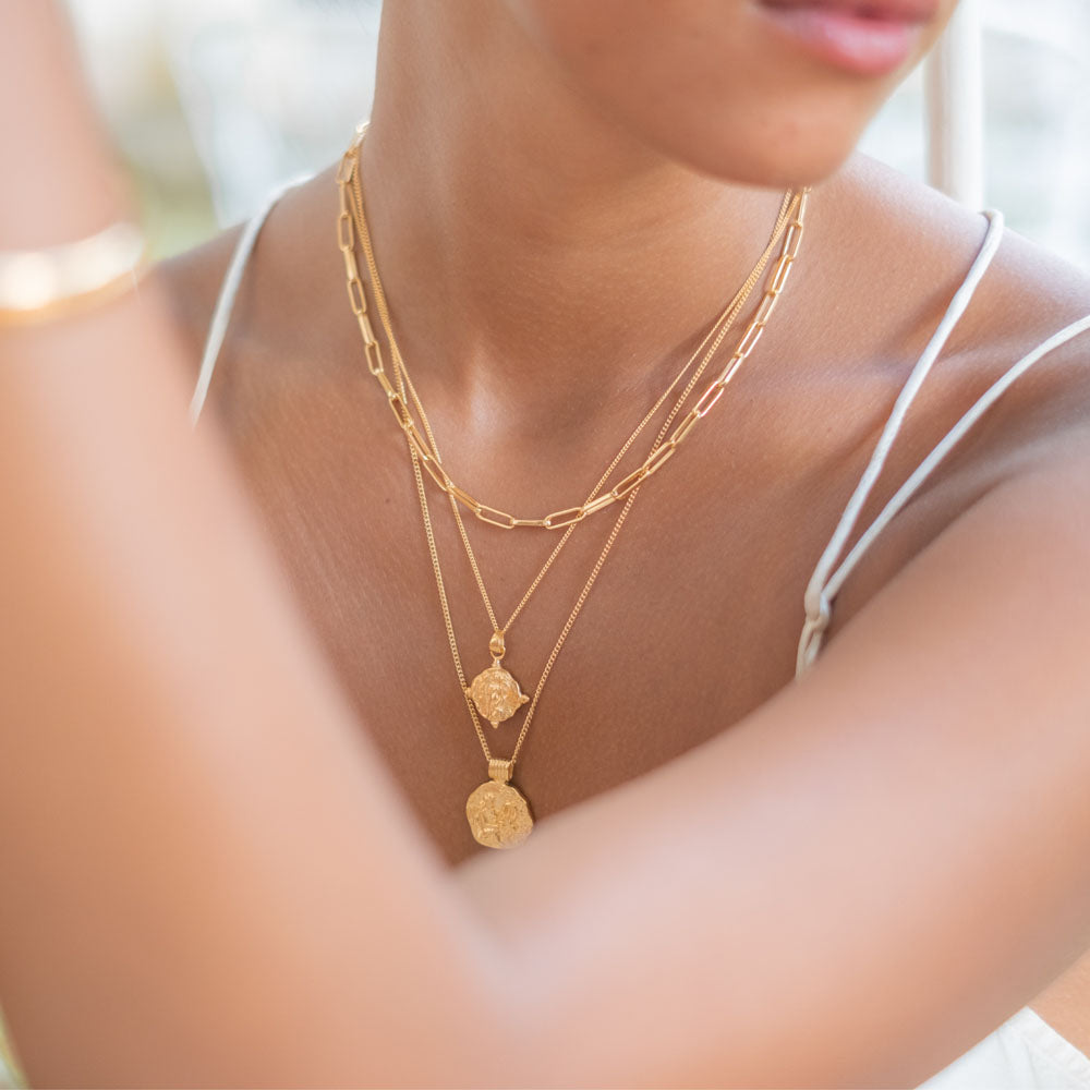 A gold necklace with a pendant featuring a religious figure designs design.