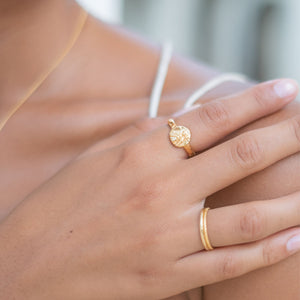 A close-up of a hand with two golden rings resting on a shoulder 