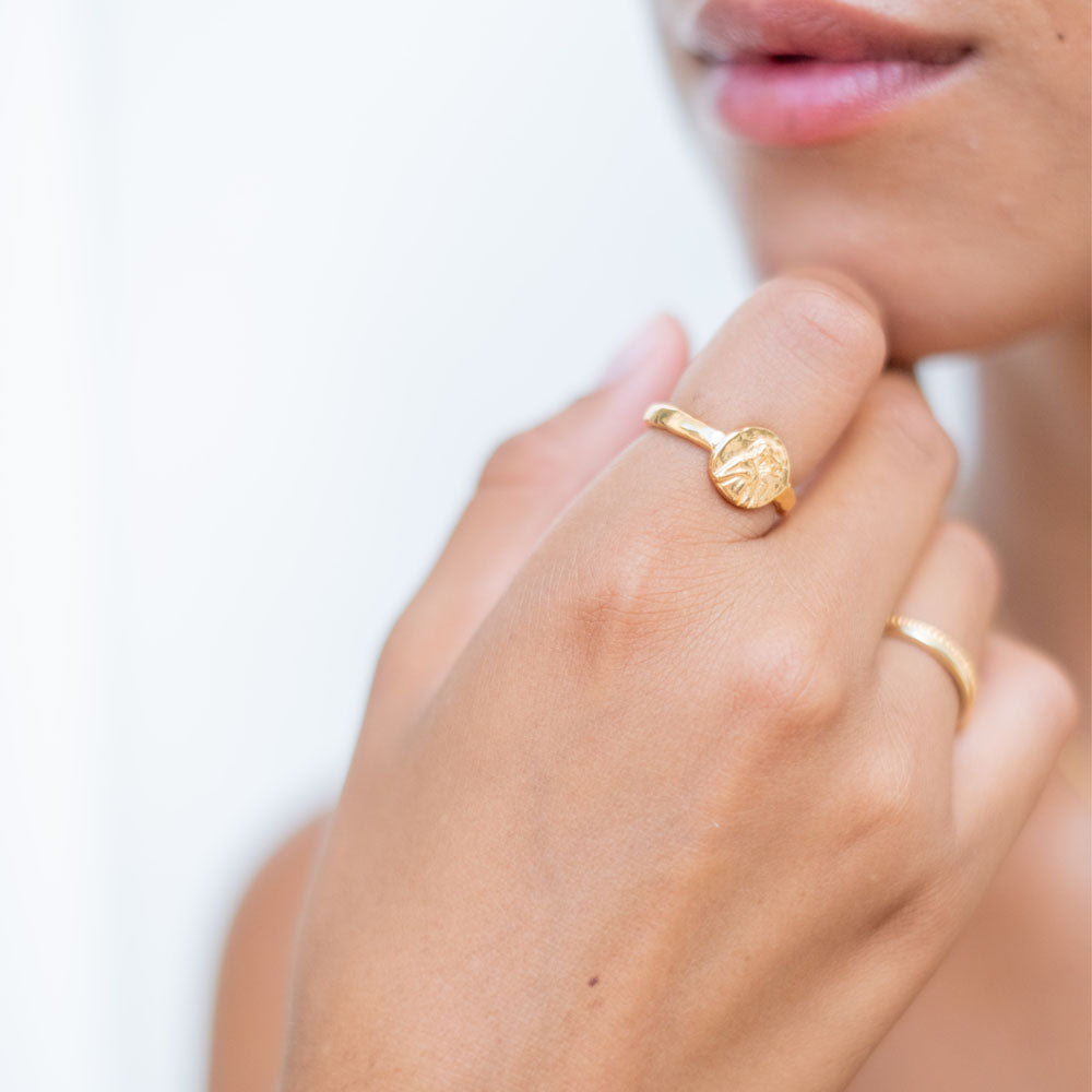 A gold ring featuring an intricately detailed depiction of a saint figure on its face.