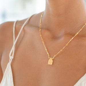 Close-up of a woman wearing a golden necklace and a white dress