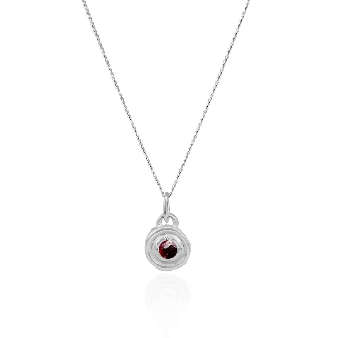 Silver necklace with a circular pendant featuring a red gemstone on a white background
