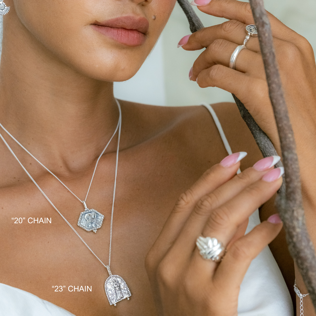 Woman wearing silver necklaces and rings with a neutral background