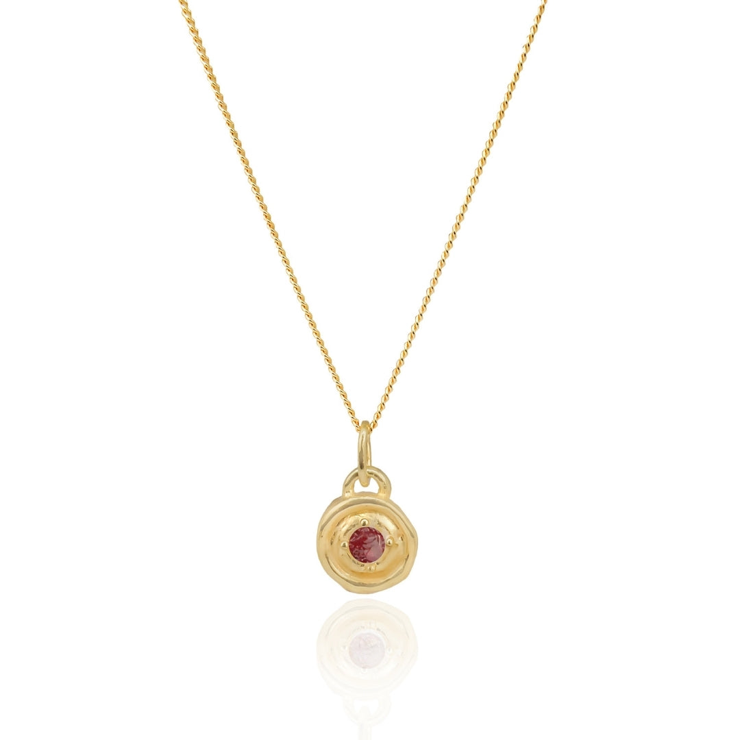 Gold necklace with a red gemstone pendant on a white background