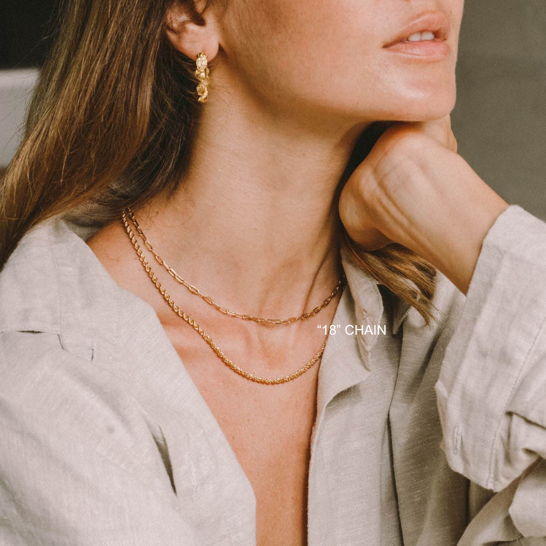Close-up of a woman wearing gold necklaces and earrings, with text '18' Chain' on a neutral background.