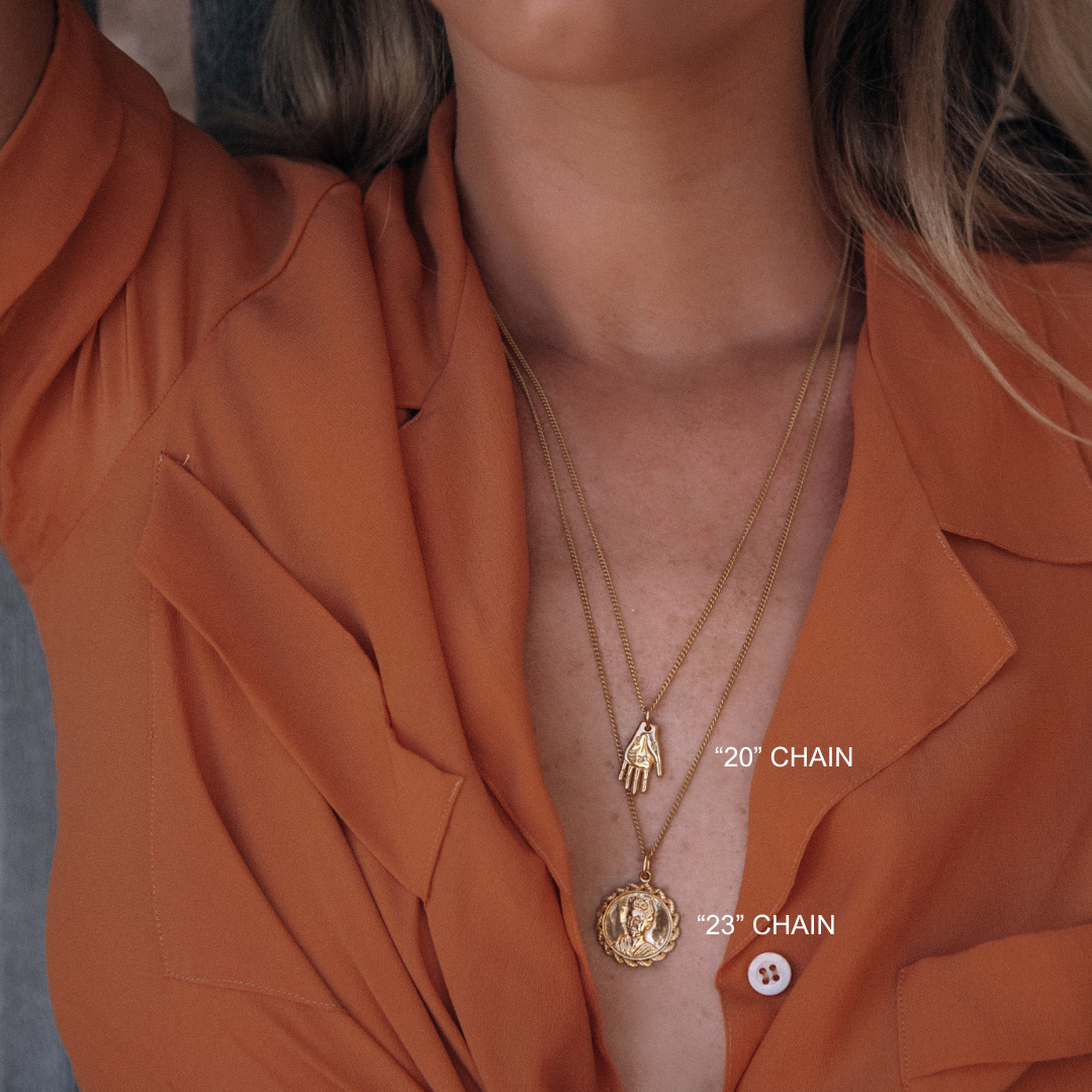 Close-up of a person wearing two gold necklaces with measurements labeled on an orange shirt.