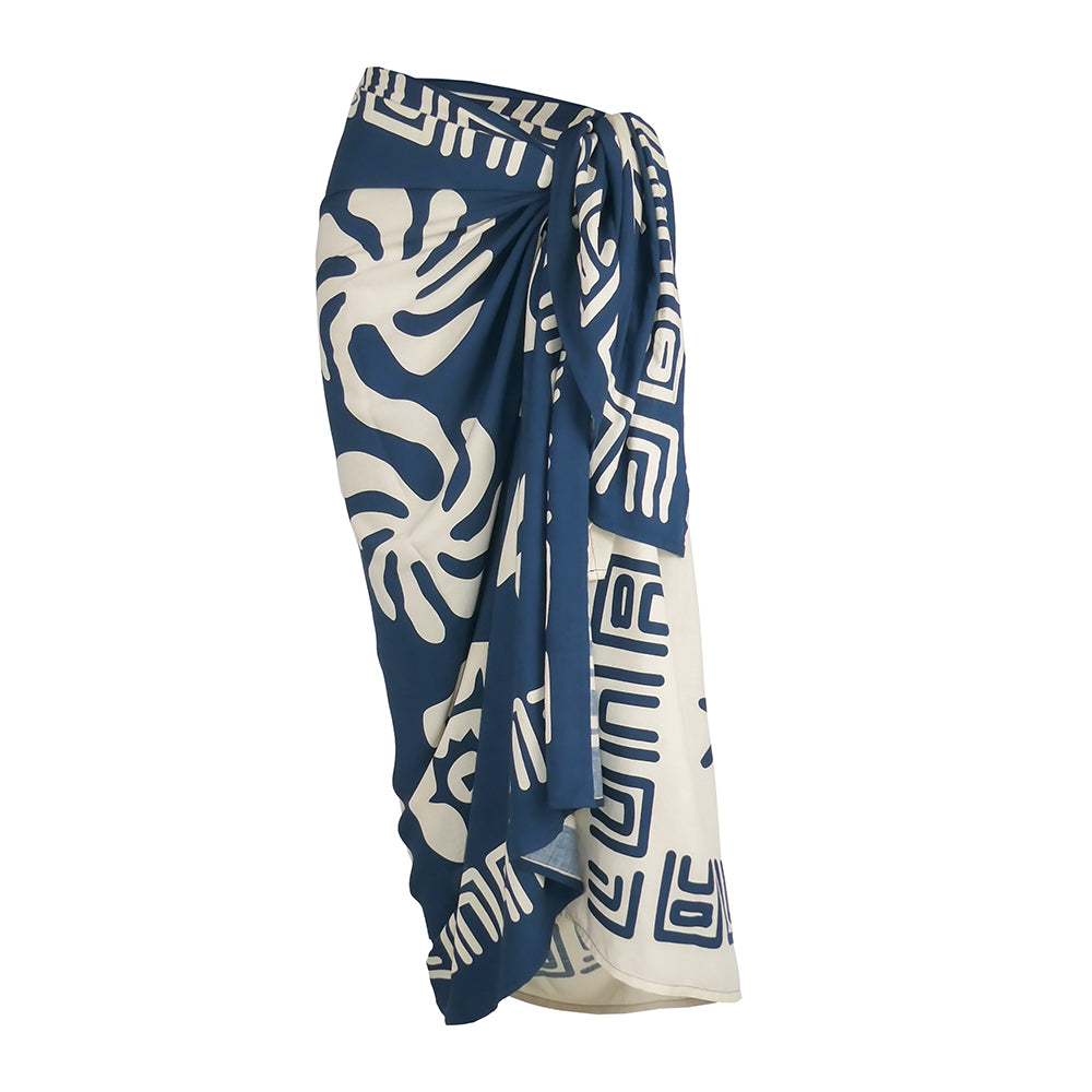 A wrap-style sarong skirt featuring a navy blue and cream tropical monstera leaf and geometric pattern, shown against a plain white background 