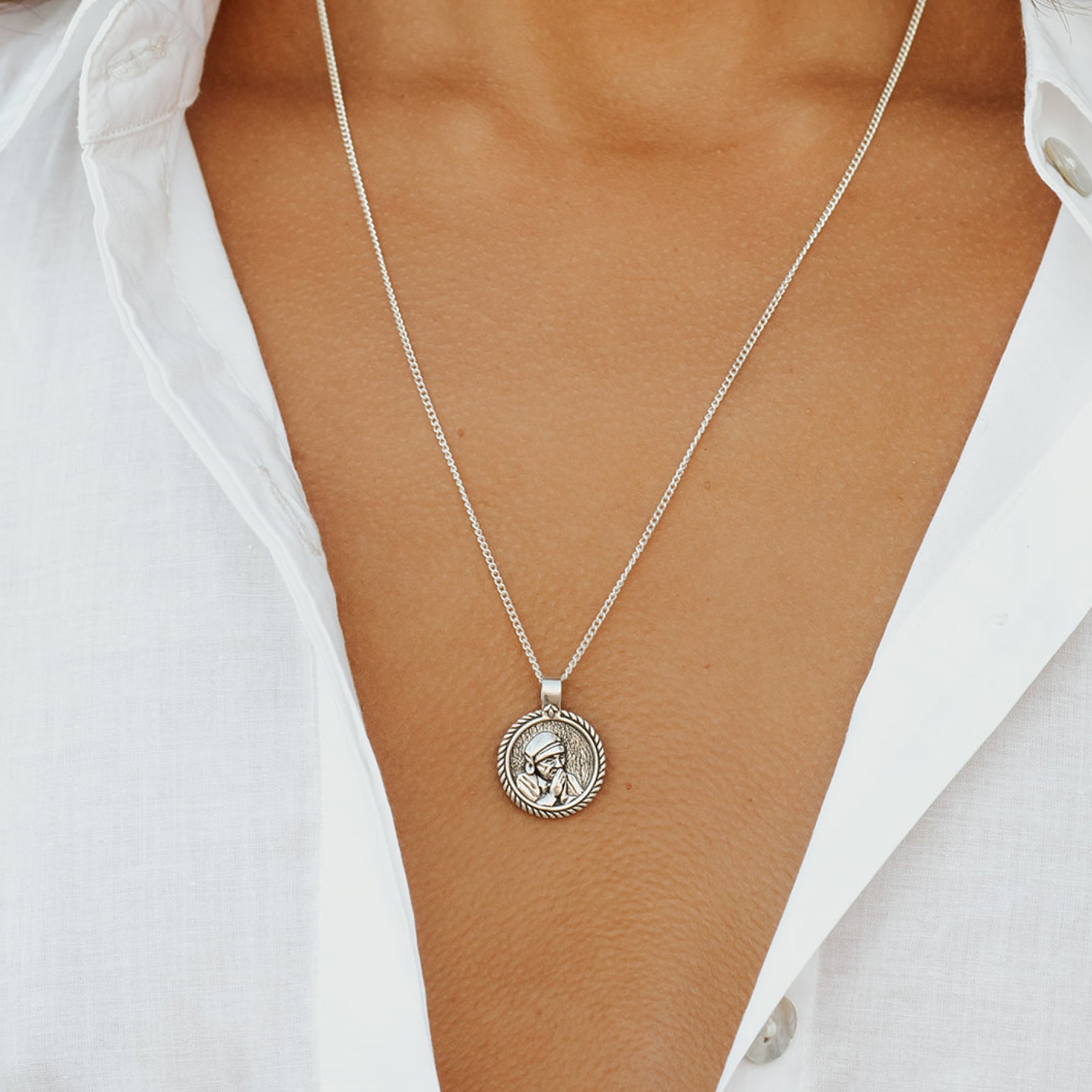 Silver necklace with a pendant on a person wearing a white shirt