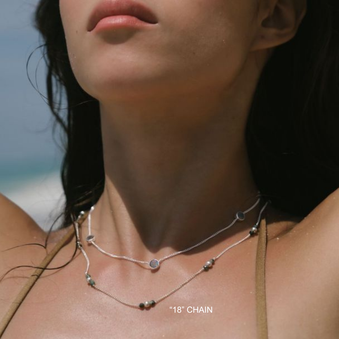 Close-up of a person wearing a silver necklace with '18' Chain text.