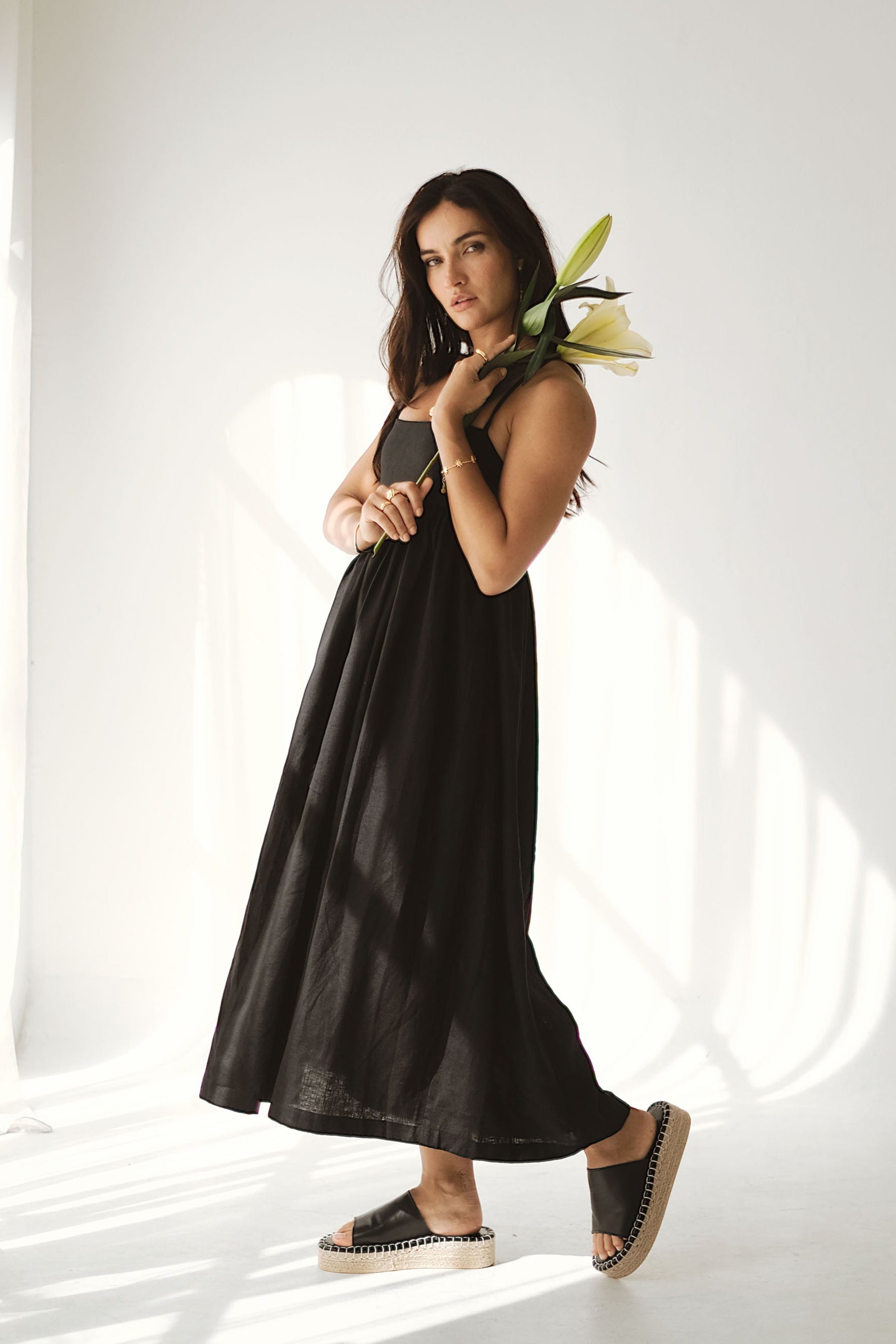 Woman in a black dress holding flowers against a white background