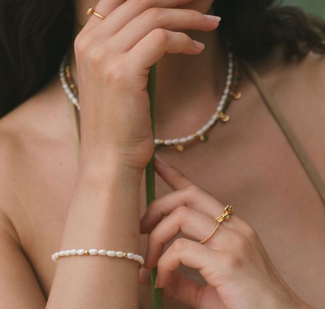 Romantic-style image of a woman with a flower and simple gold jewelry