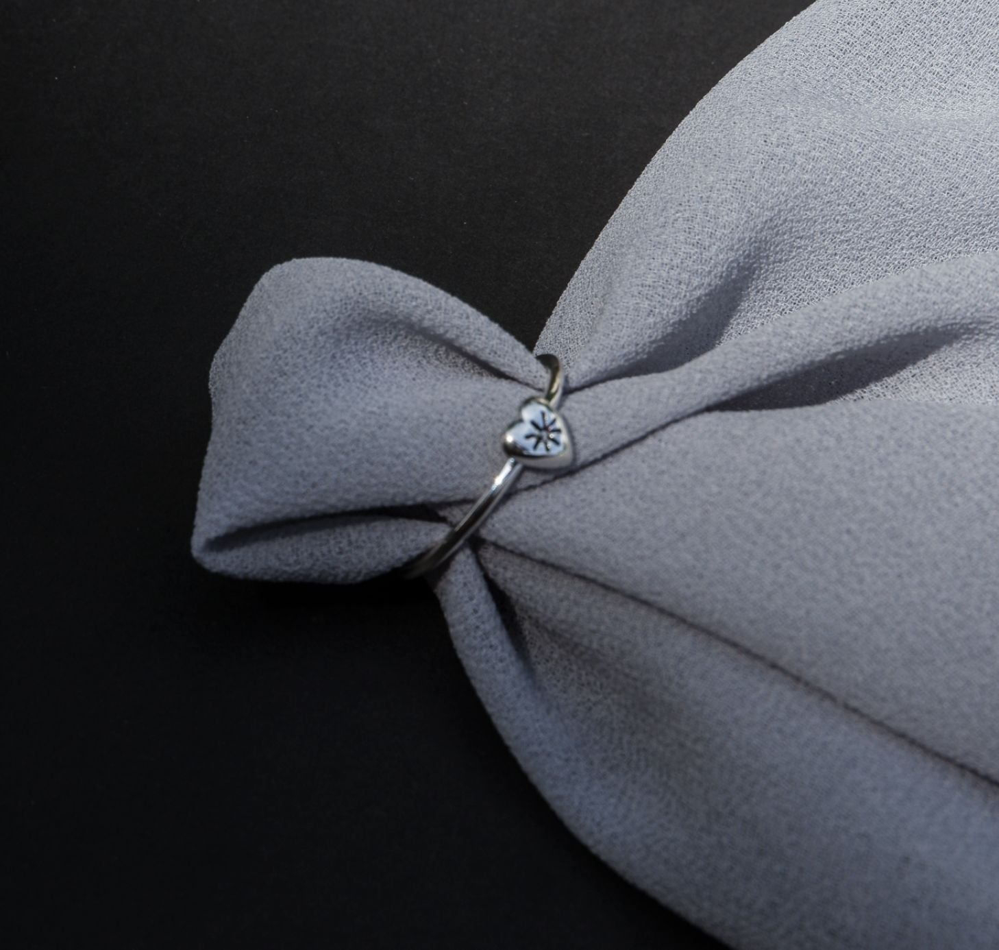 Mini Silver heart ring on piece of cloth fabric