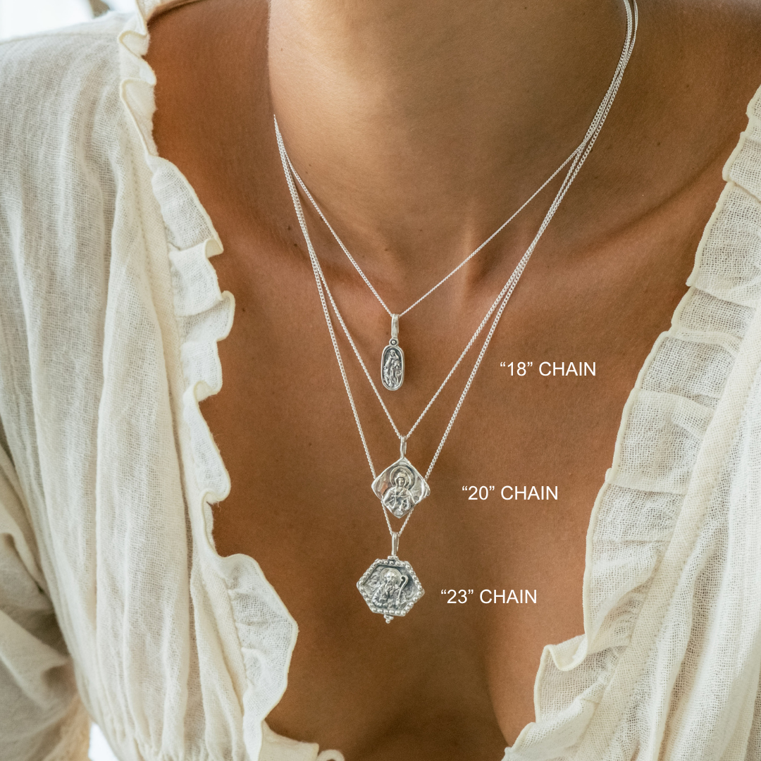 Necklace with three chain lengths displayed on a person wearing a white top.