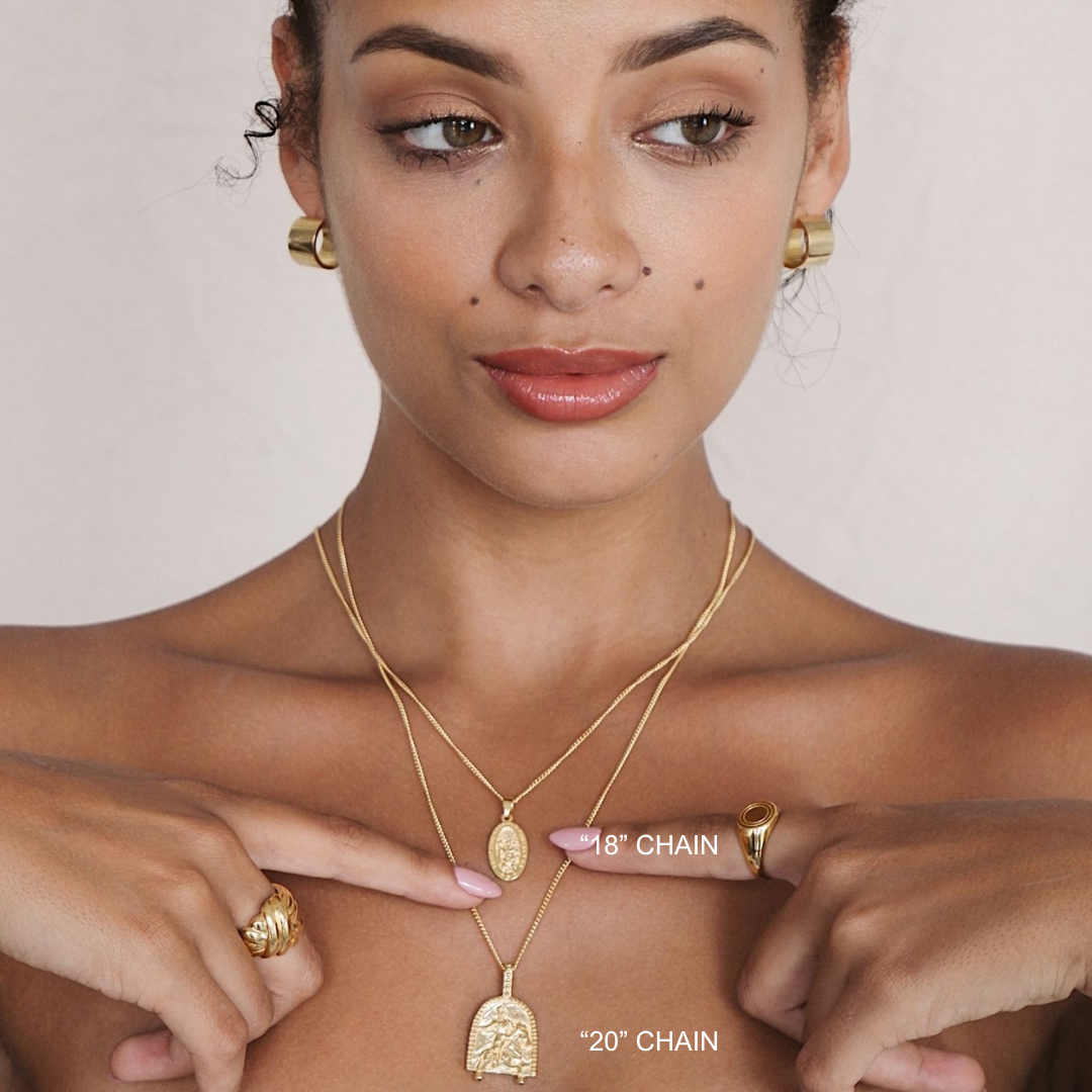 Woman wearing gold necklaces and rings with a plain background