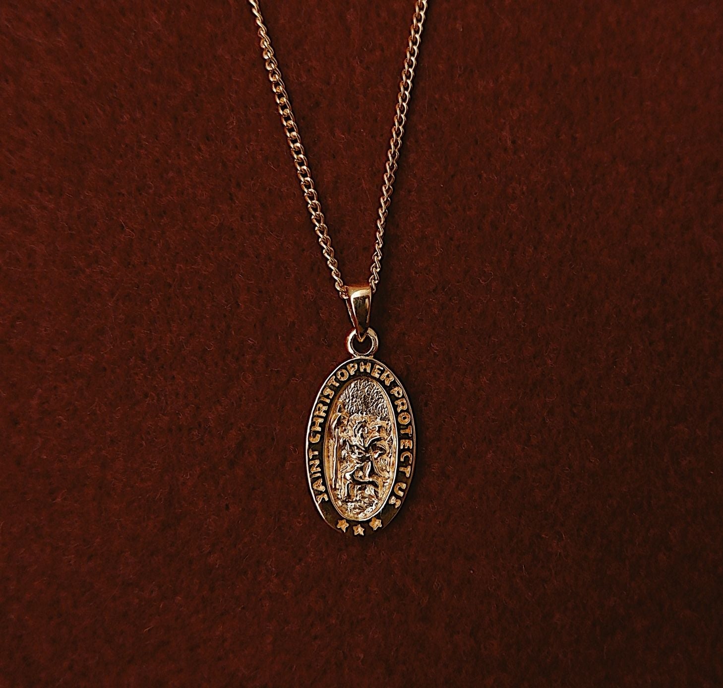 St Christopher  necklace gold flat lay in red fabric