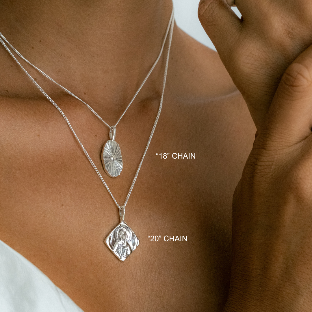 Silver necklaces with pendants on a person's neck, labeled '18' chain' and '20' chain'.