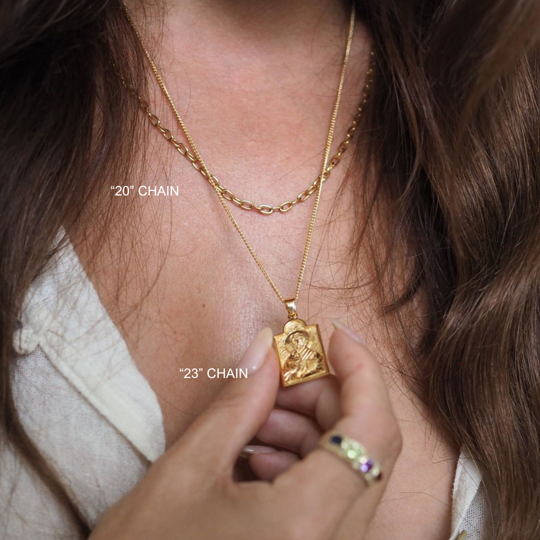 Close-up of a person wearing two gold necklaces with visible chain lengths.